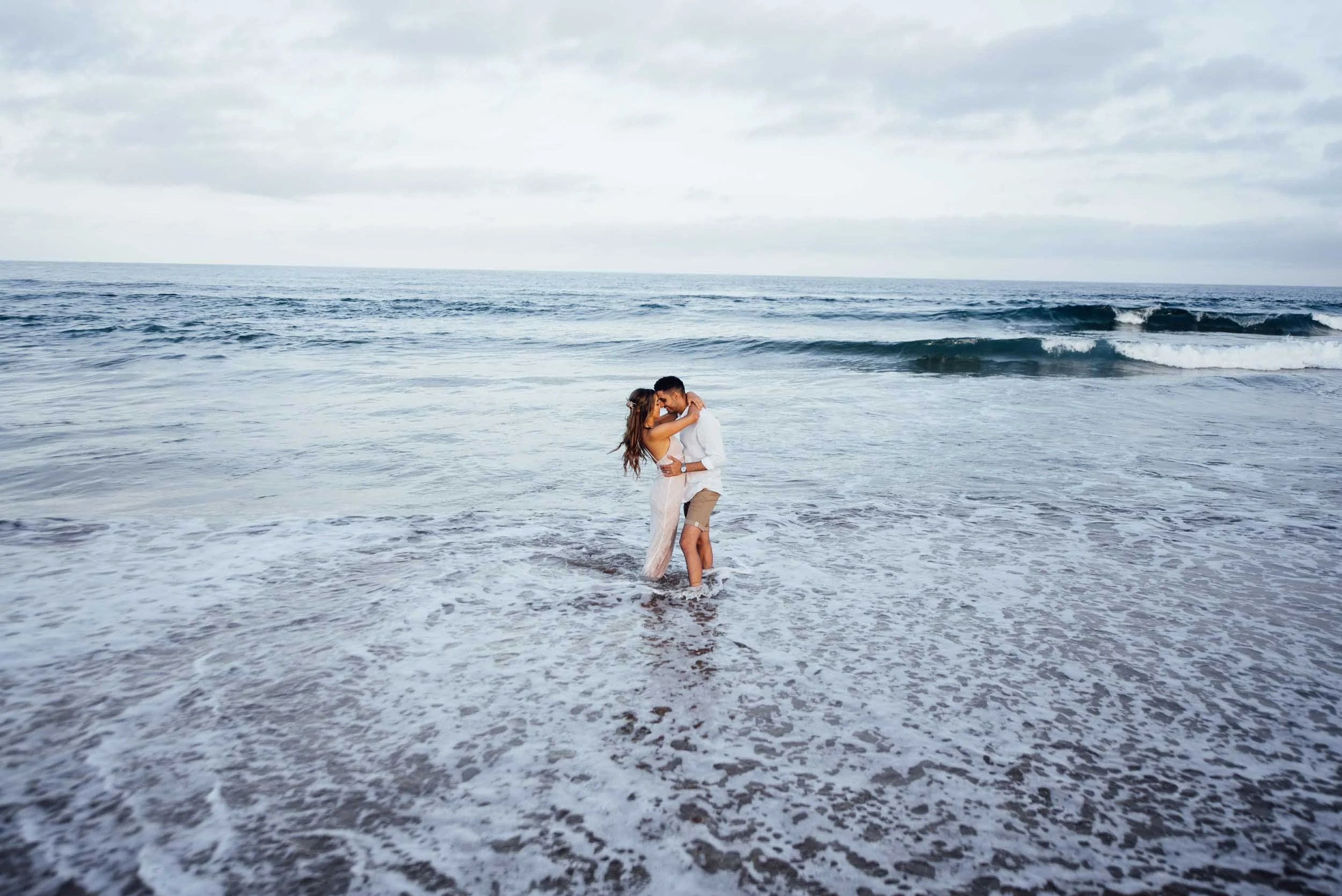 pregnancy photography shoot of kissing couple in the water