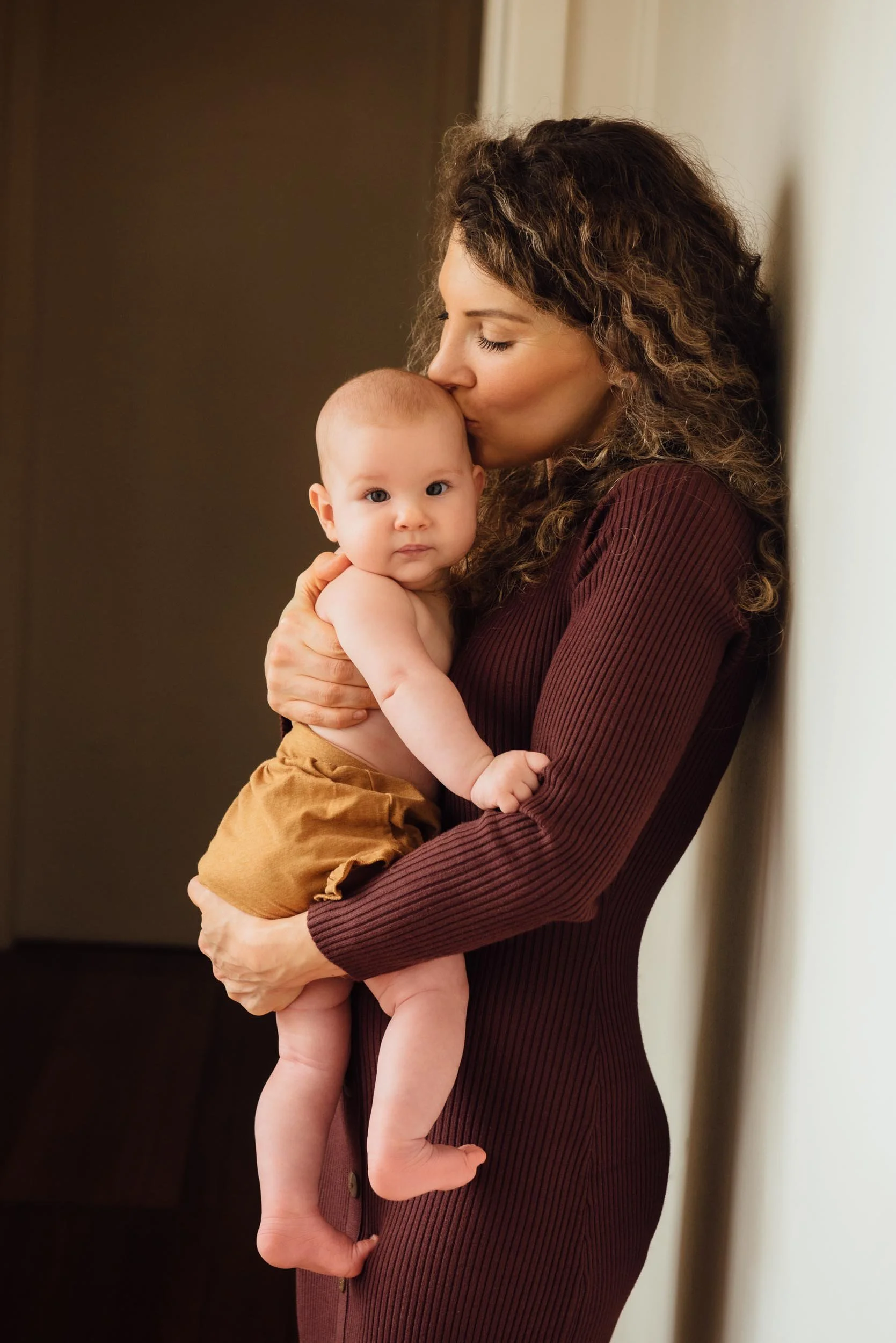 mother kissing baby in hallway