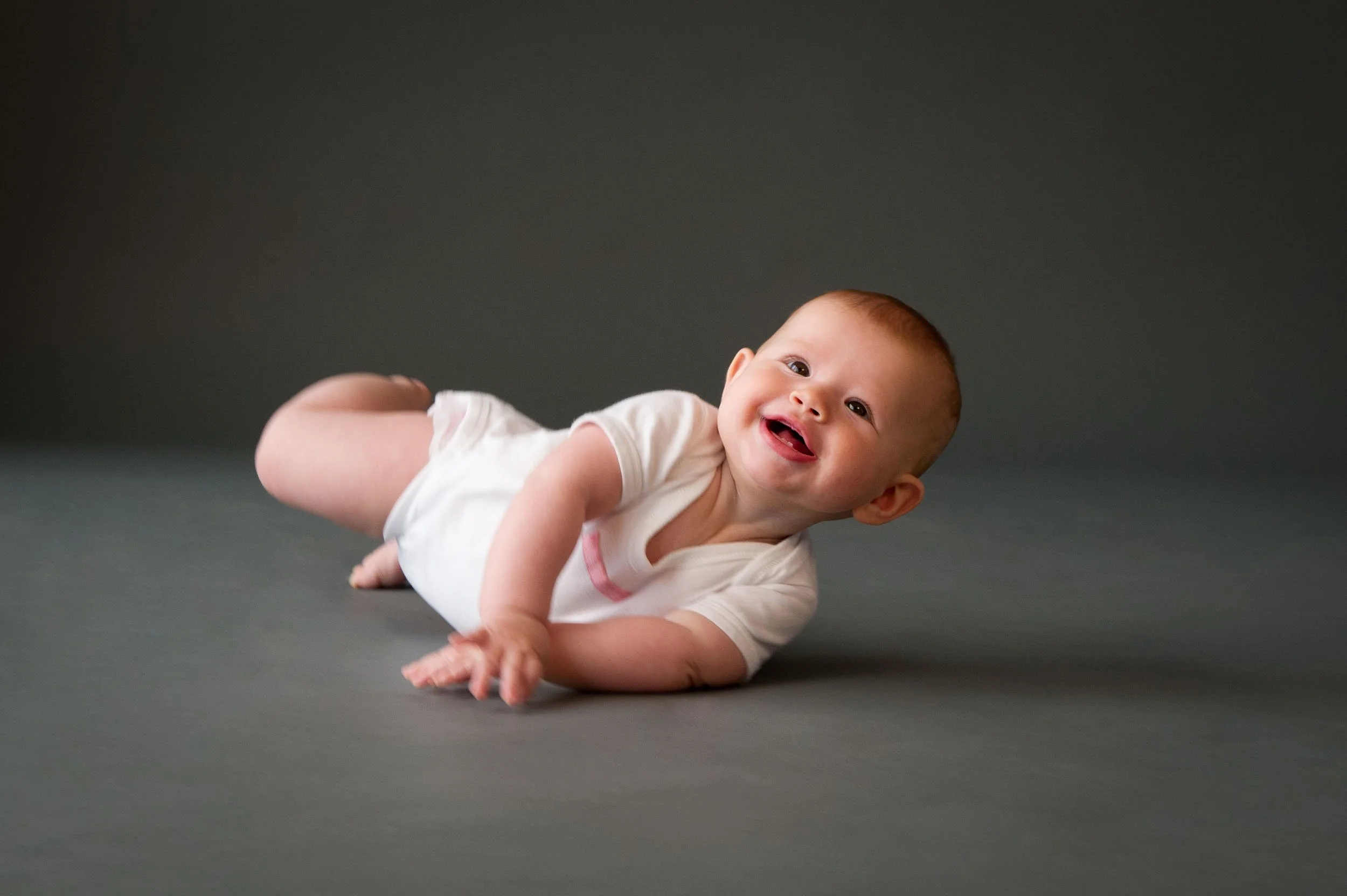 laughing baby lying on photography studio background