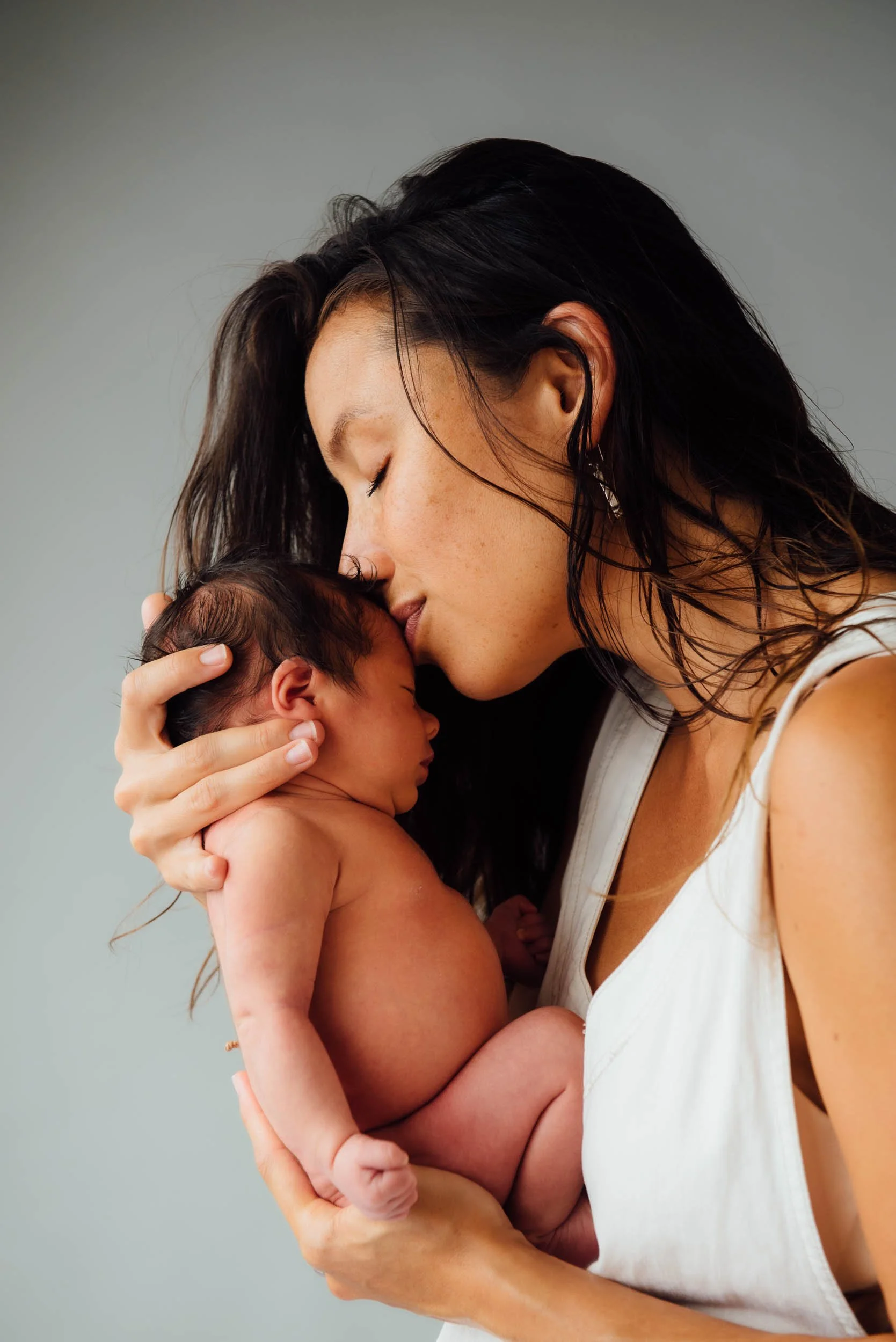 mother kissing her newborn's head