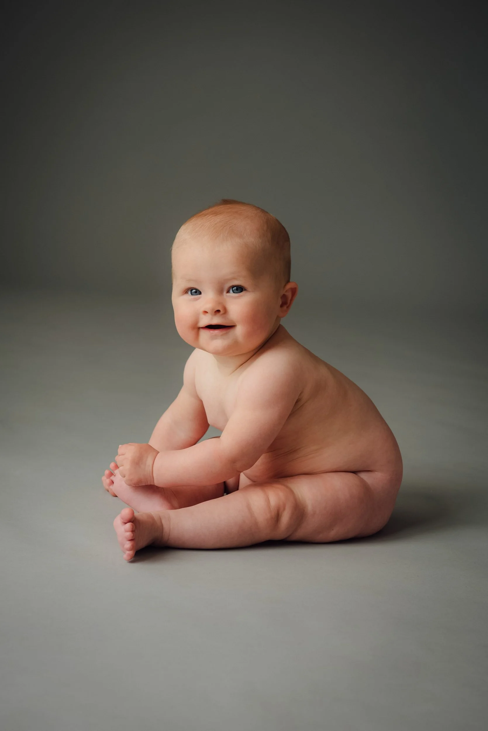 studio baby photography of girl sitting on background smiling
