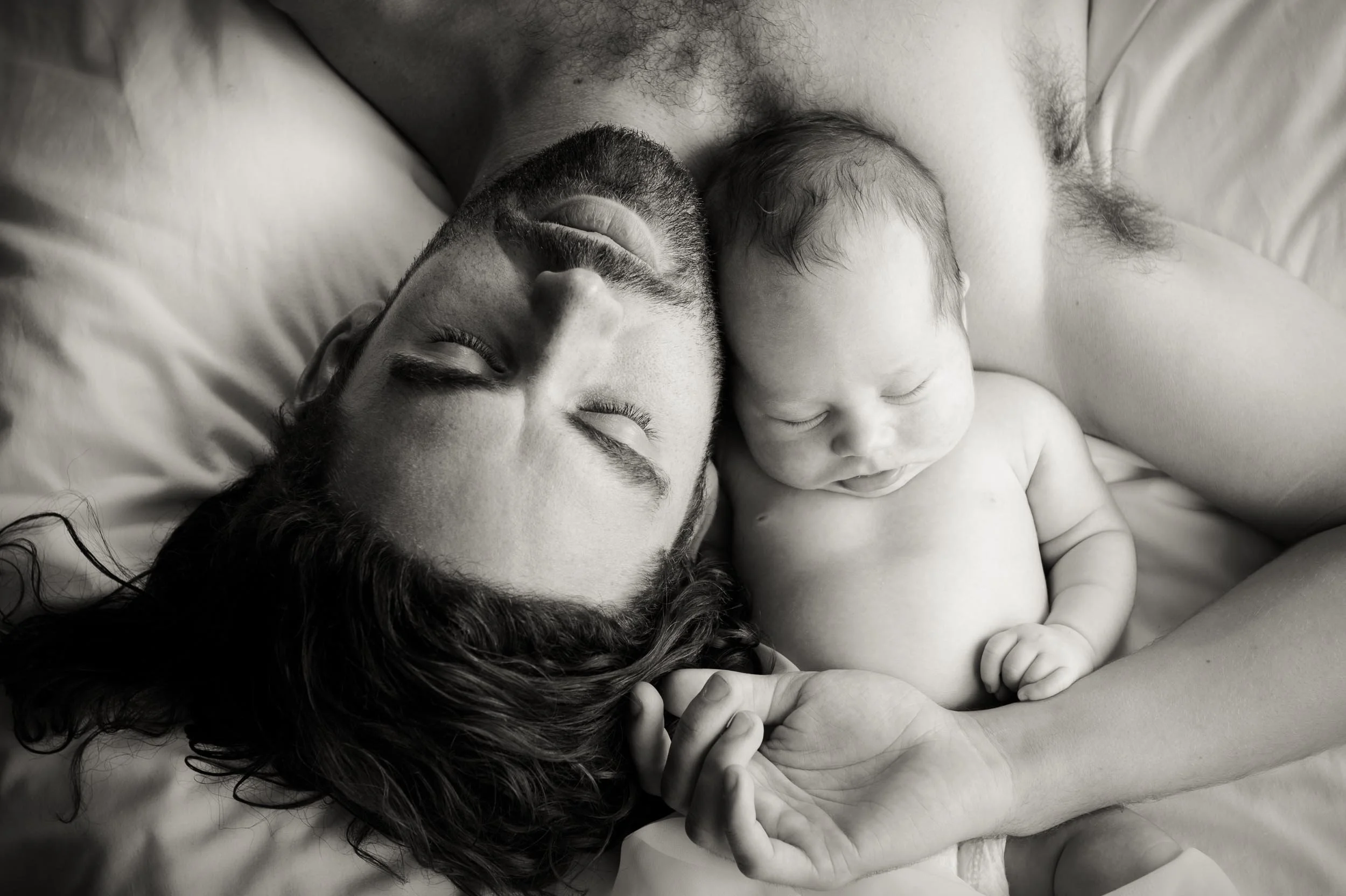 newborn photoshoot of father sleeping next to his son