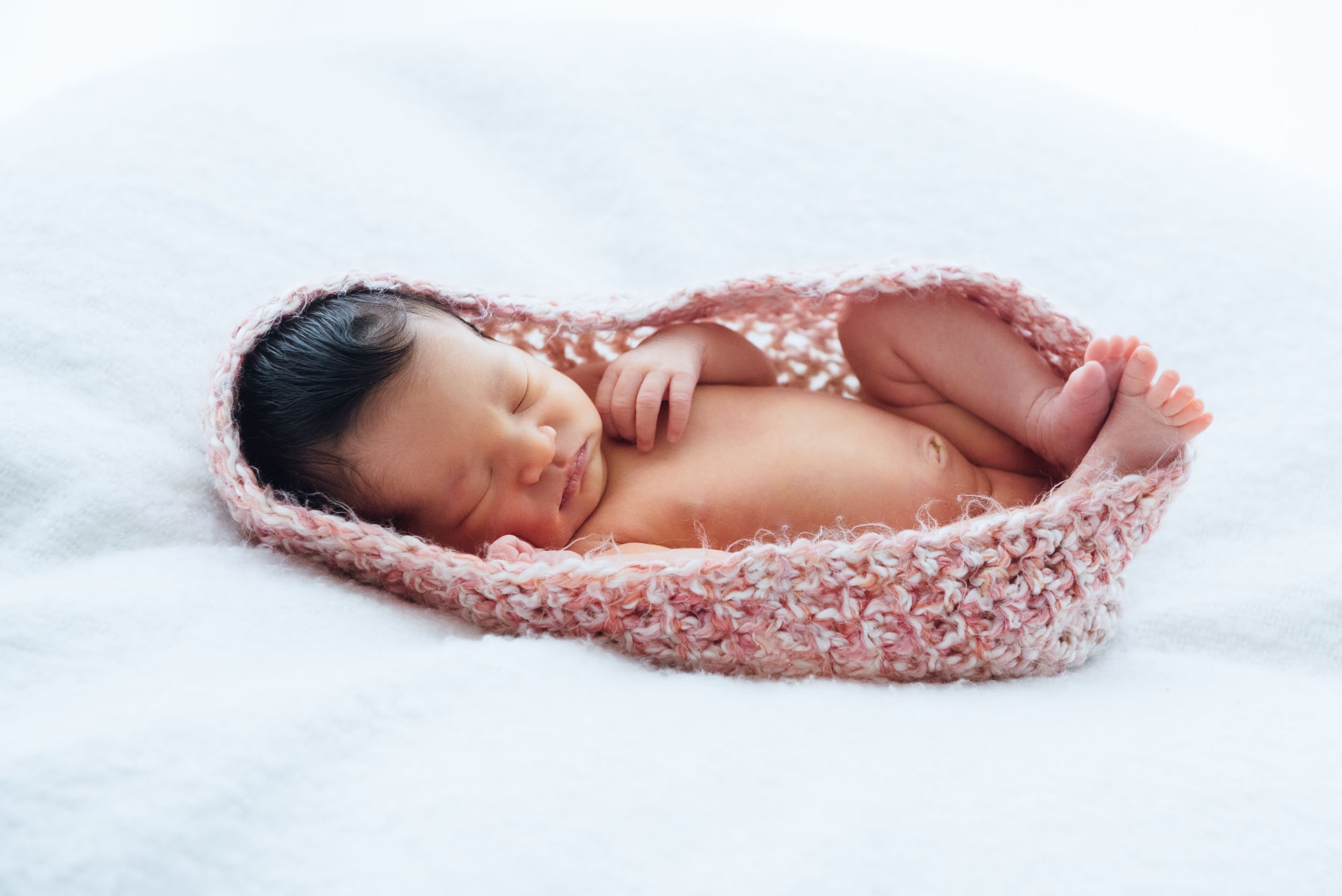 newborn photoshoot of sleeping baby in a crocheted cocoon