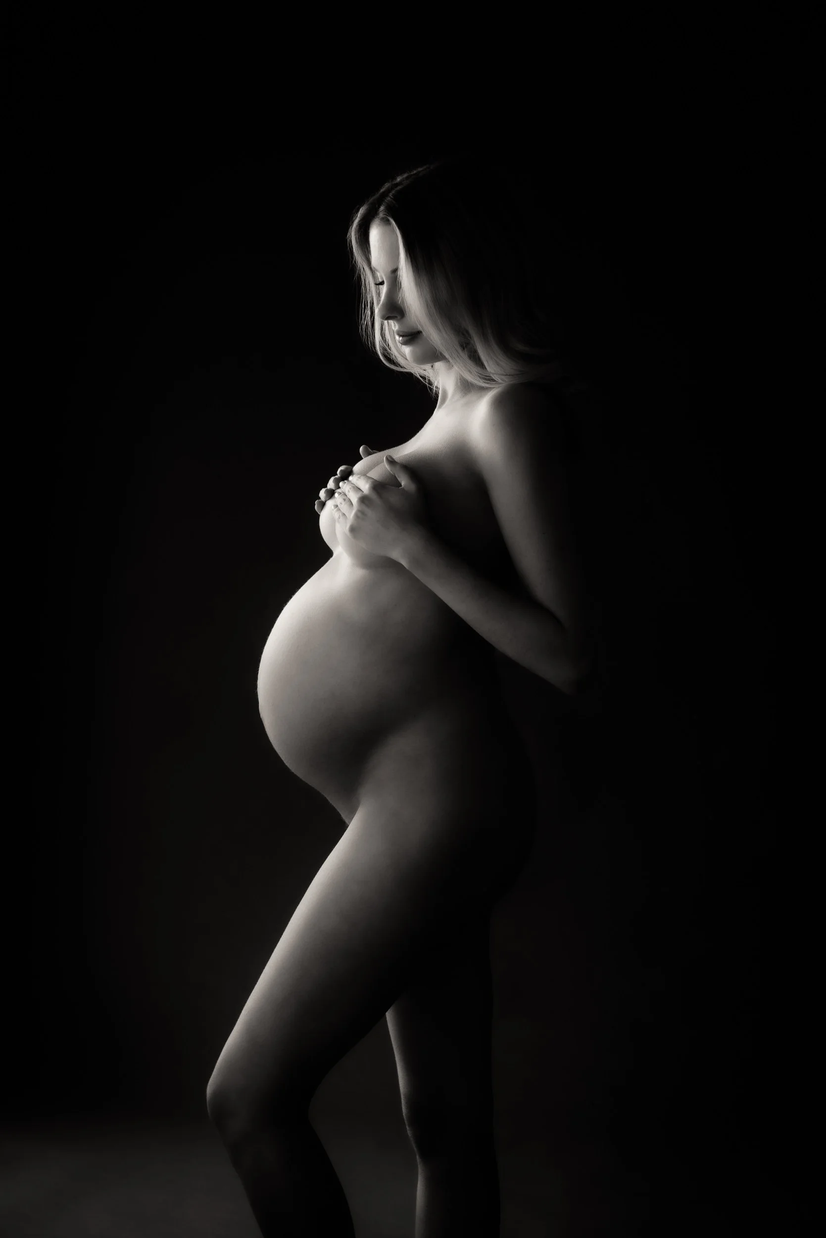 elegant maternity portrait of a woman with hands-on breast