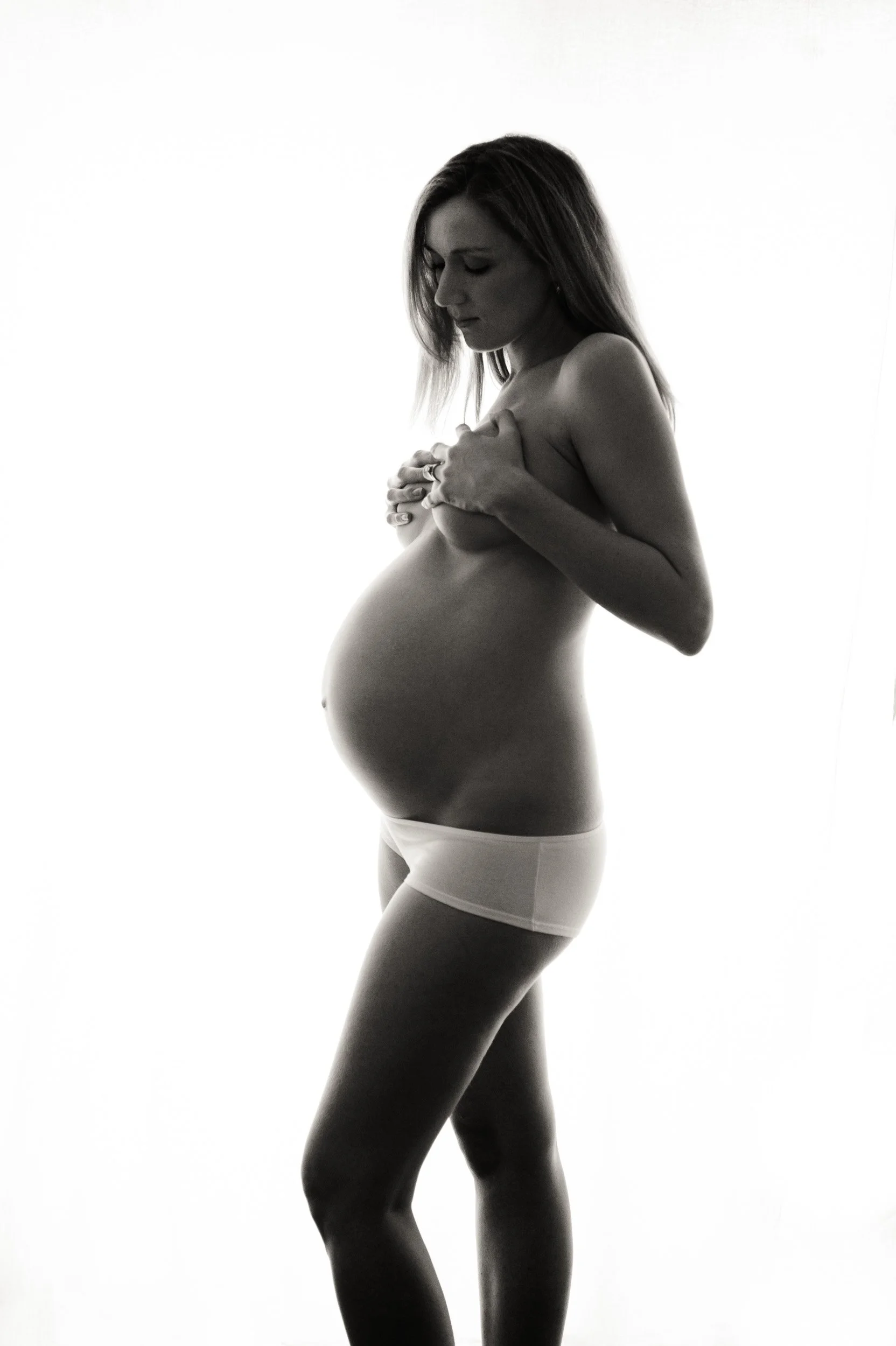 Maternity photoshoot of a woman in white undies.