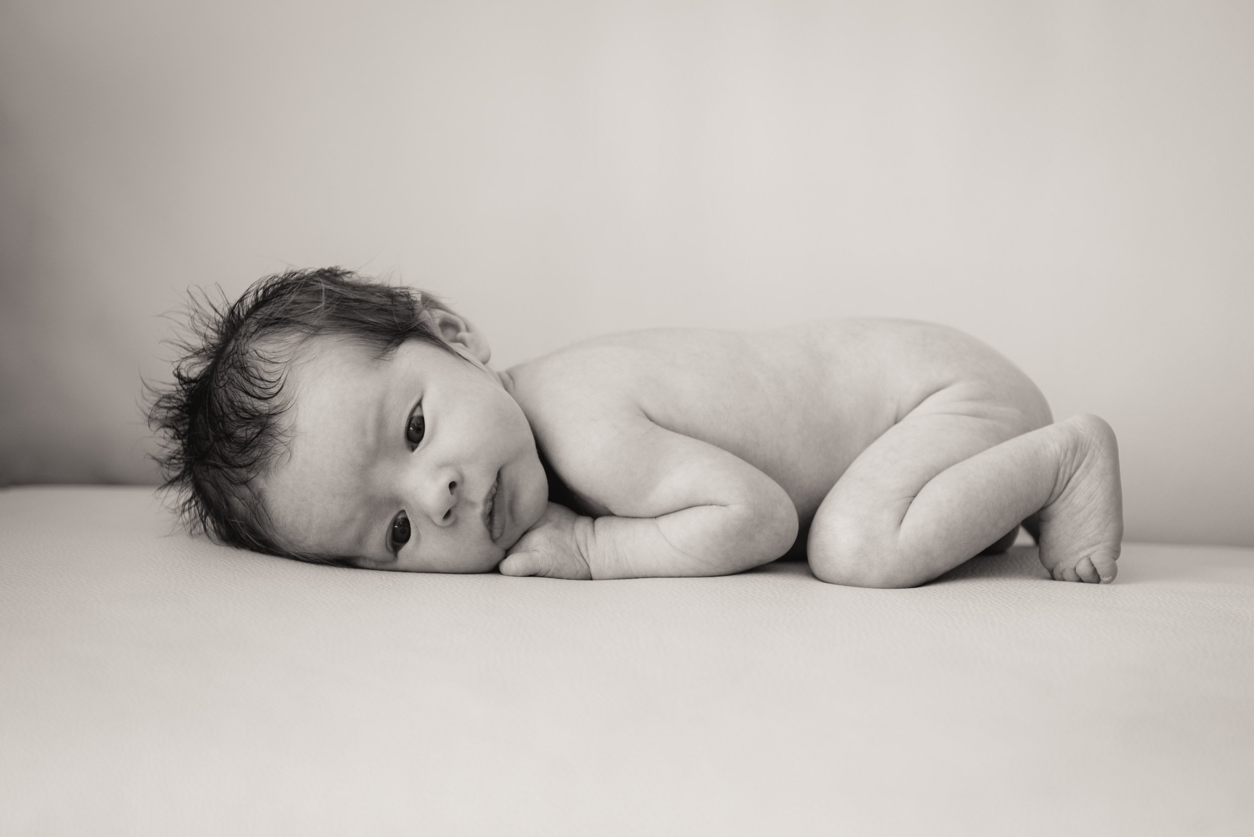newborn lying on tummy on sofa