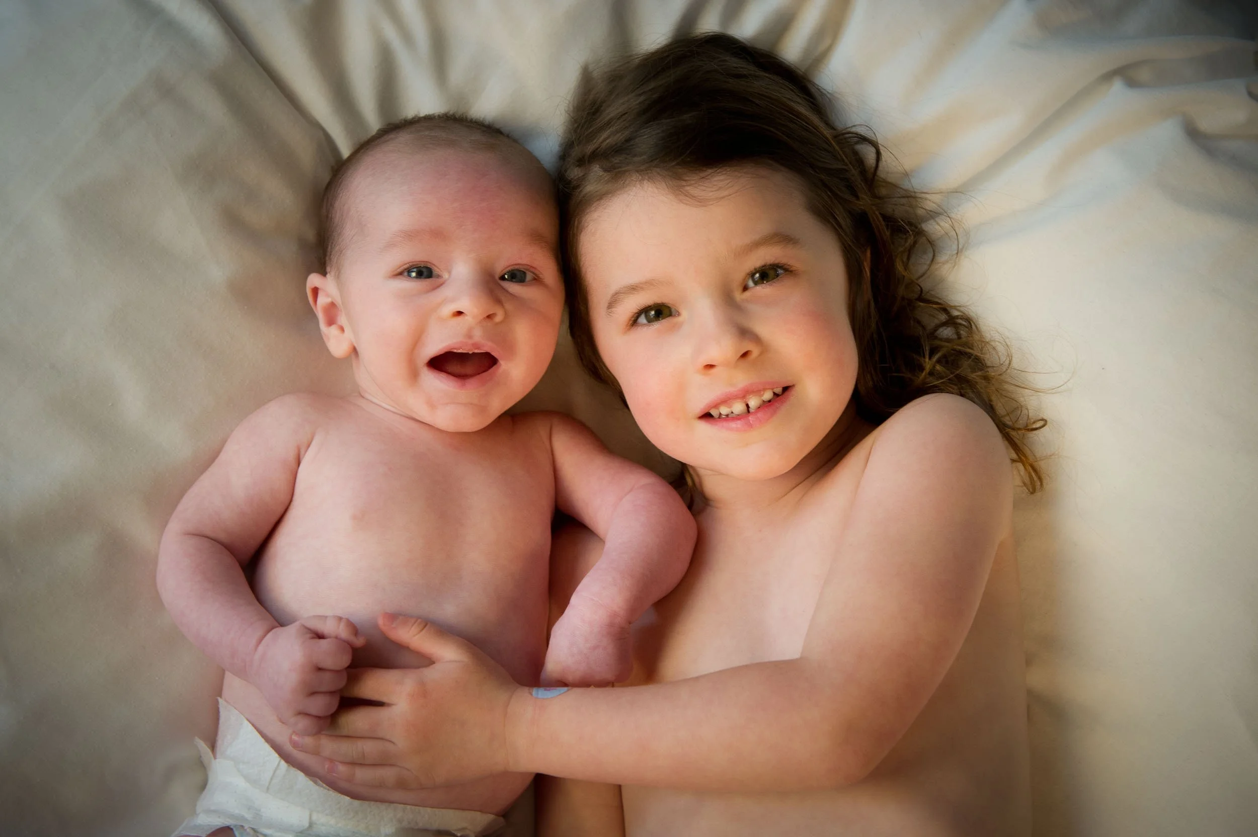 smiling sister cuddling her baby brother