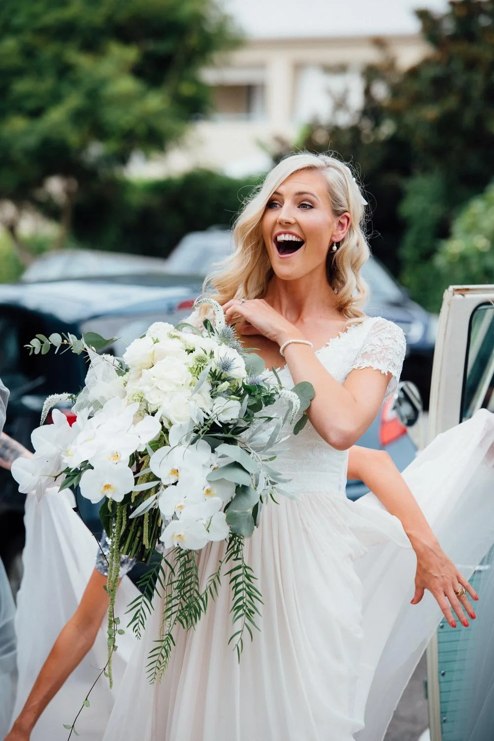 Smiling and happy Bride arriving for the wedding ceremony with a big bunch of flowers