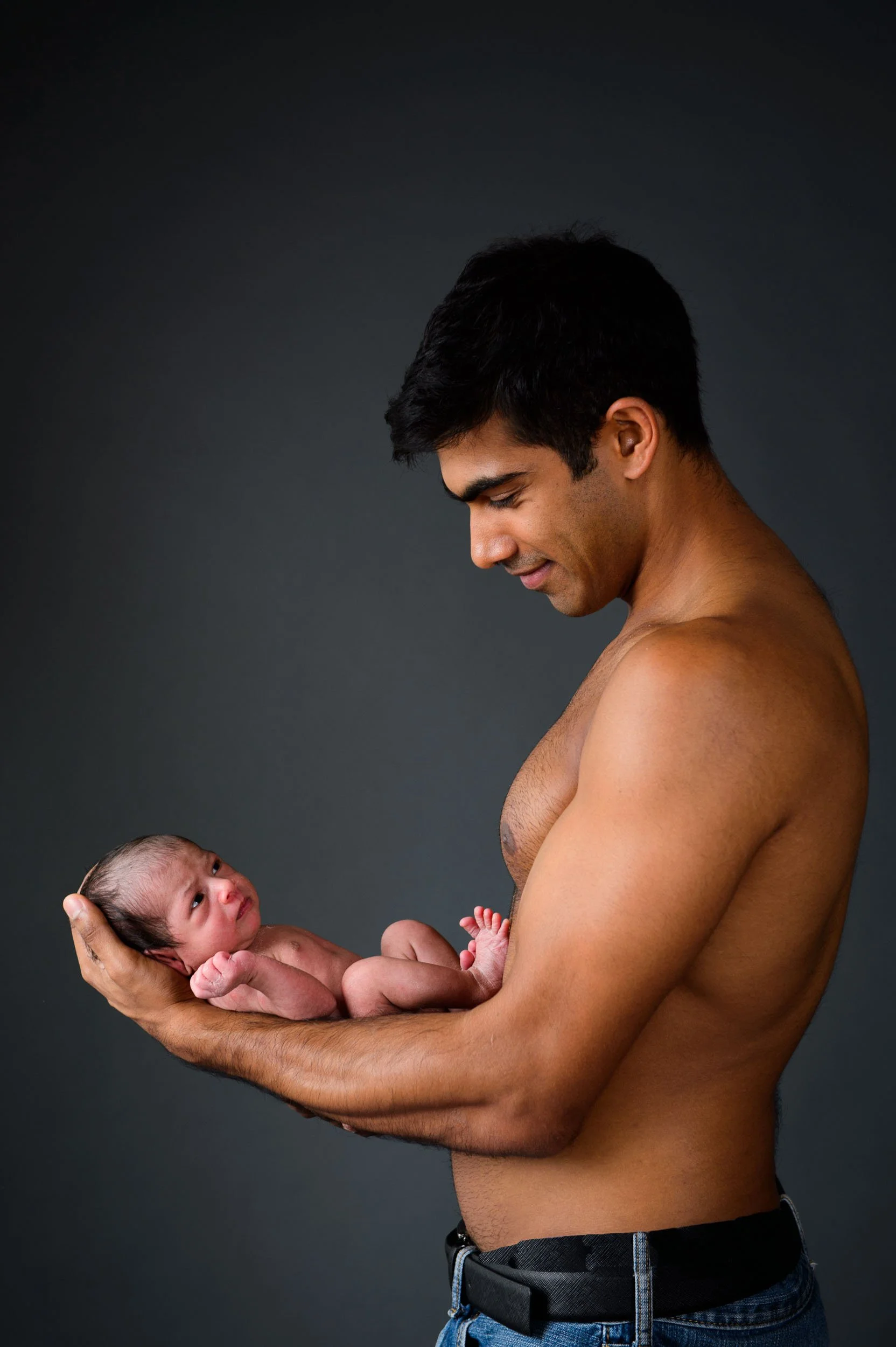 topless father holding son on his arm for a newborn photoshoot