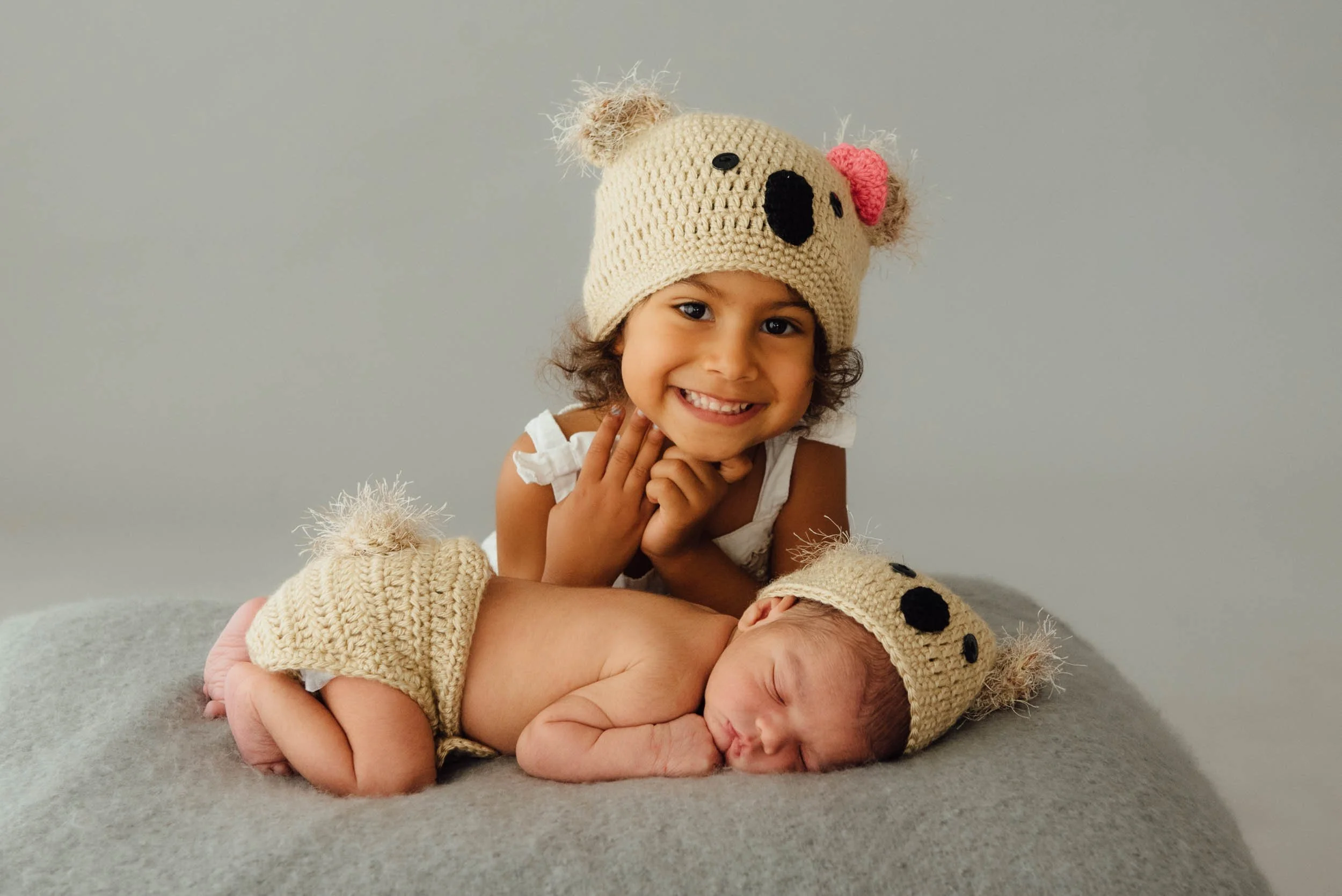family newborn photography of baby and big sister wearing matching crocheted hats
