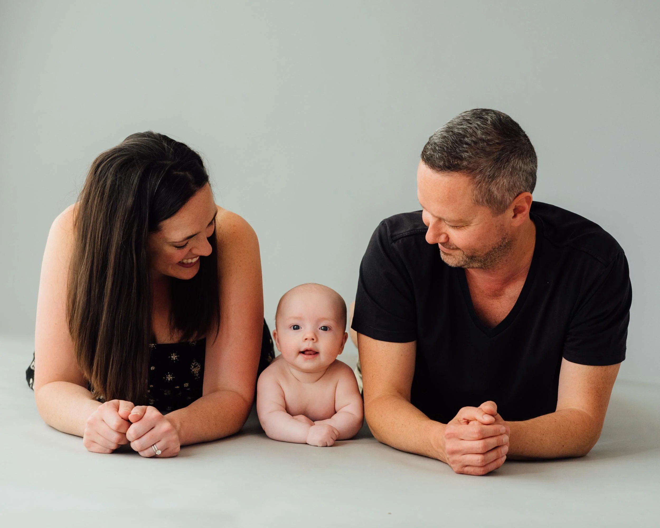 baby photoshoot of 4 month old lying on studio floor between his parents