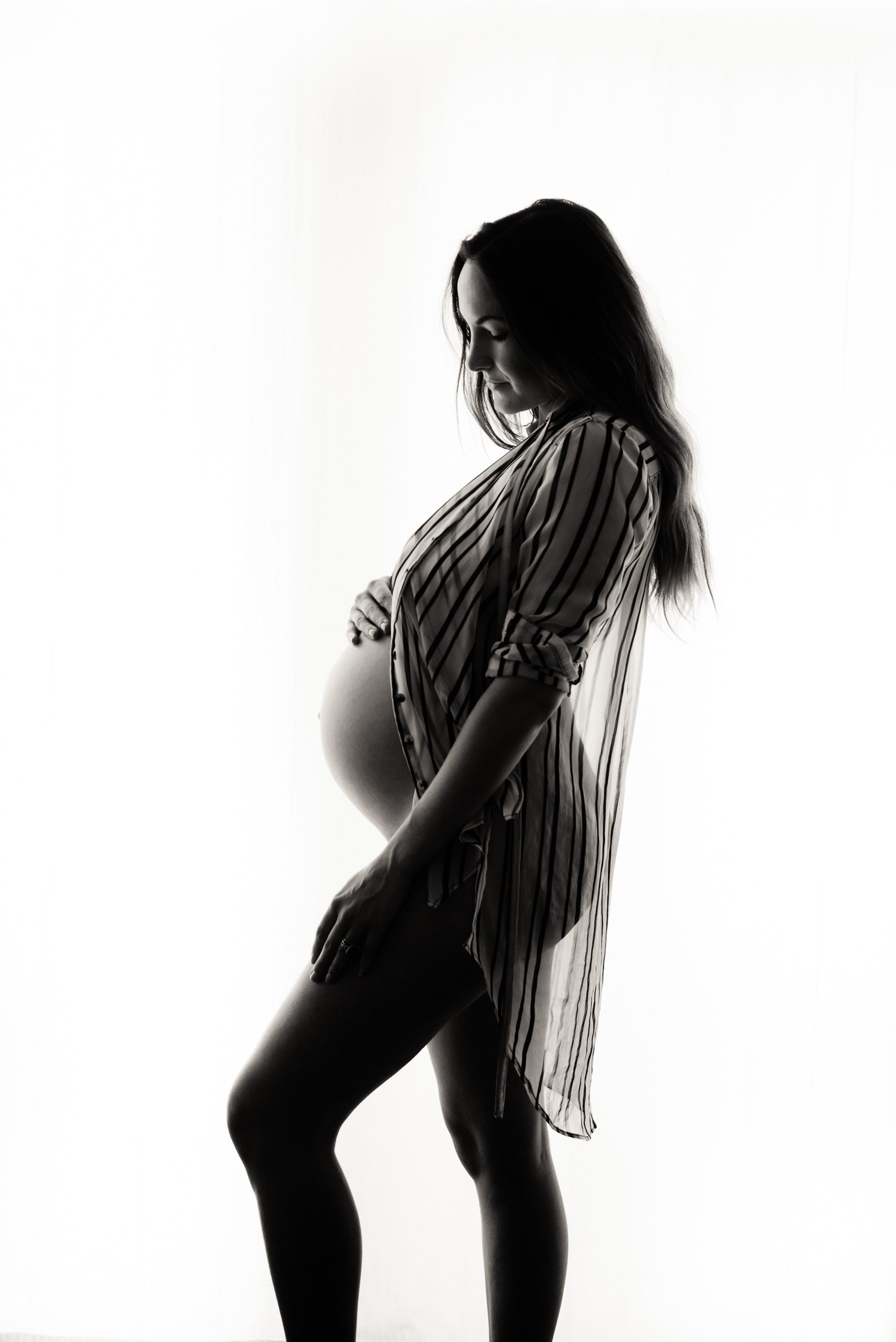 Black and white maternity photography silhouette of woman wearing shirt 