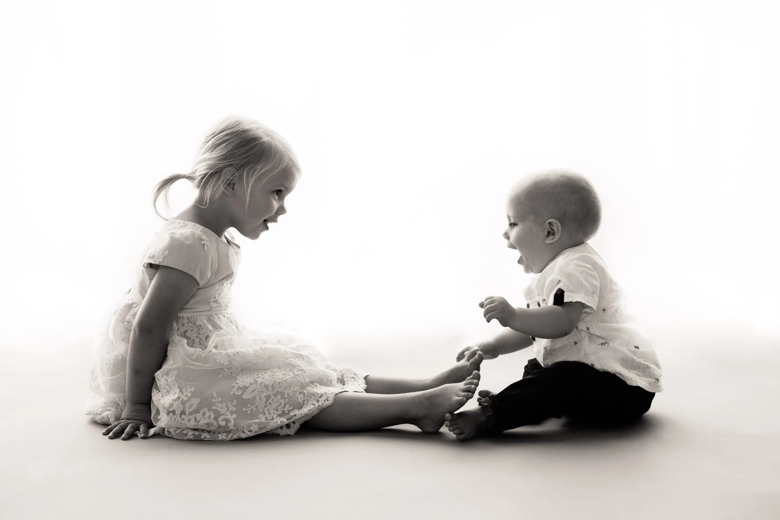 silhouette baby photography of girl and her 6 month old brother laughing