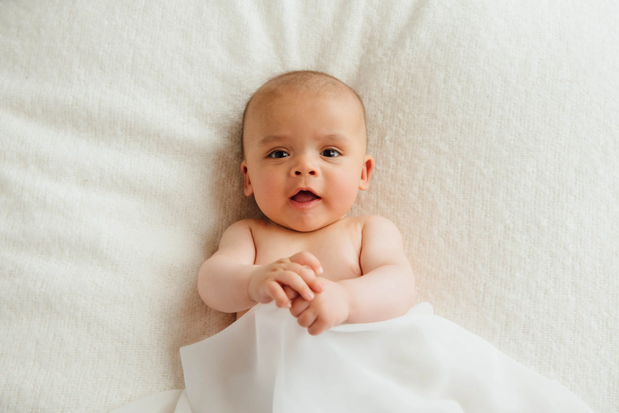 5 month old lying on pillow and smiling during a baby photography session