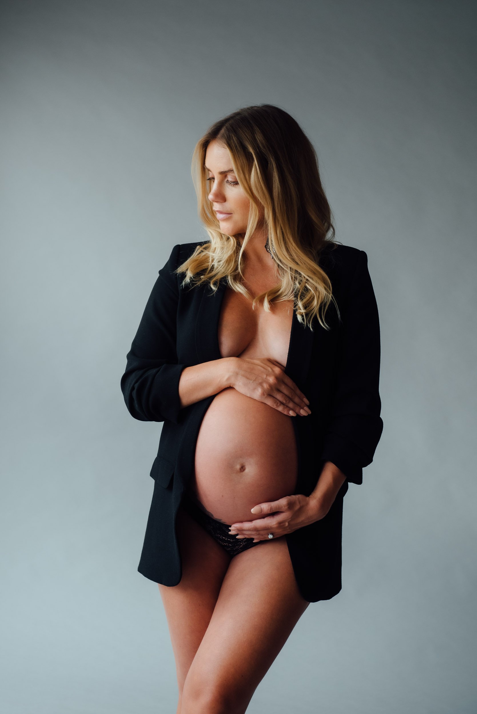 stylish maternity photoshoot of woman in a black jacket