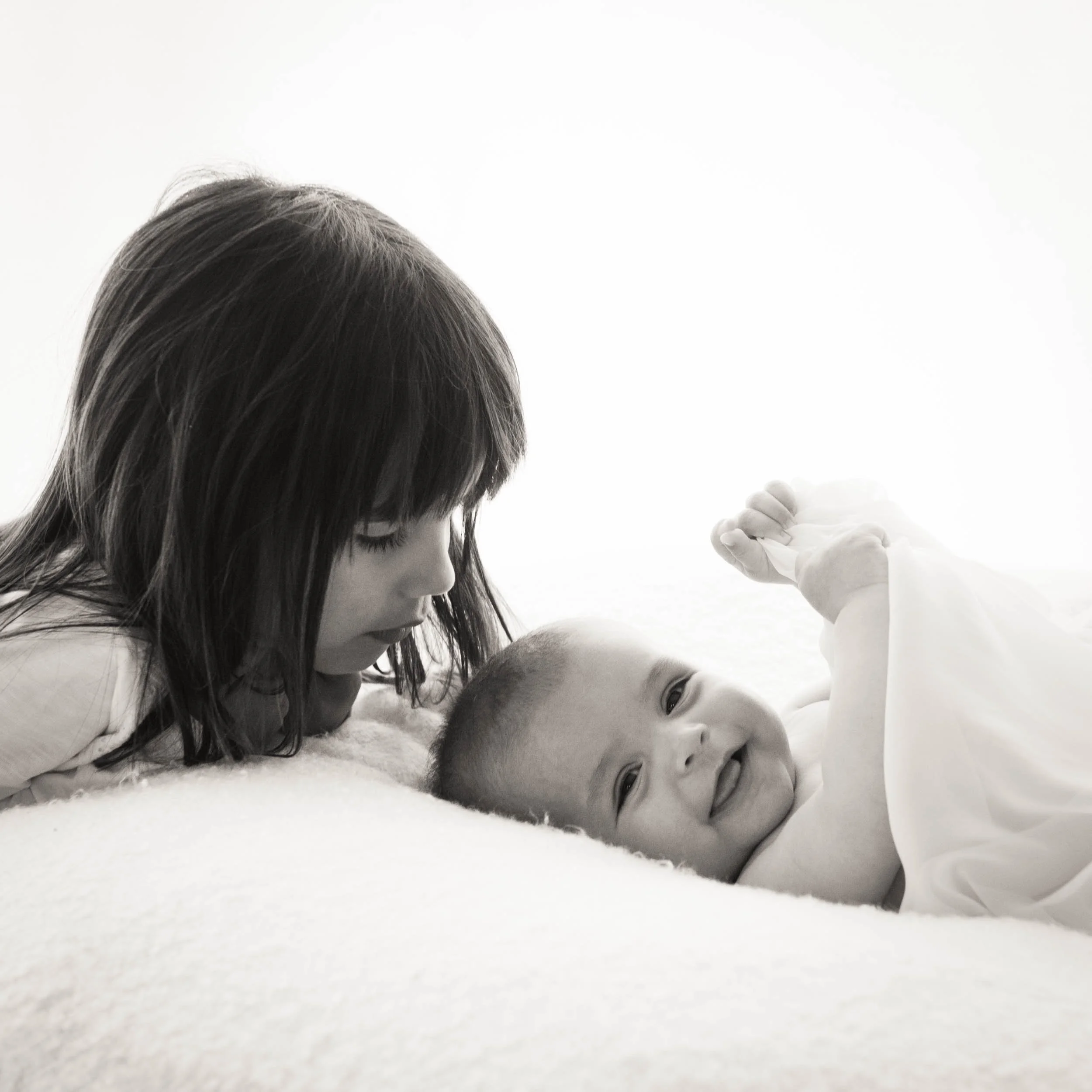 6 year old girl looking at her baby brother laughing