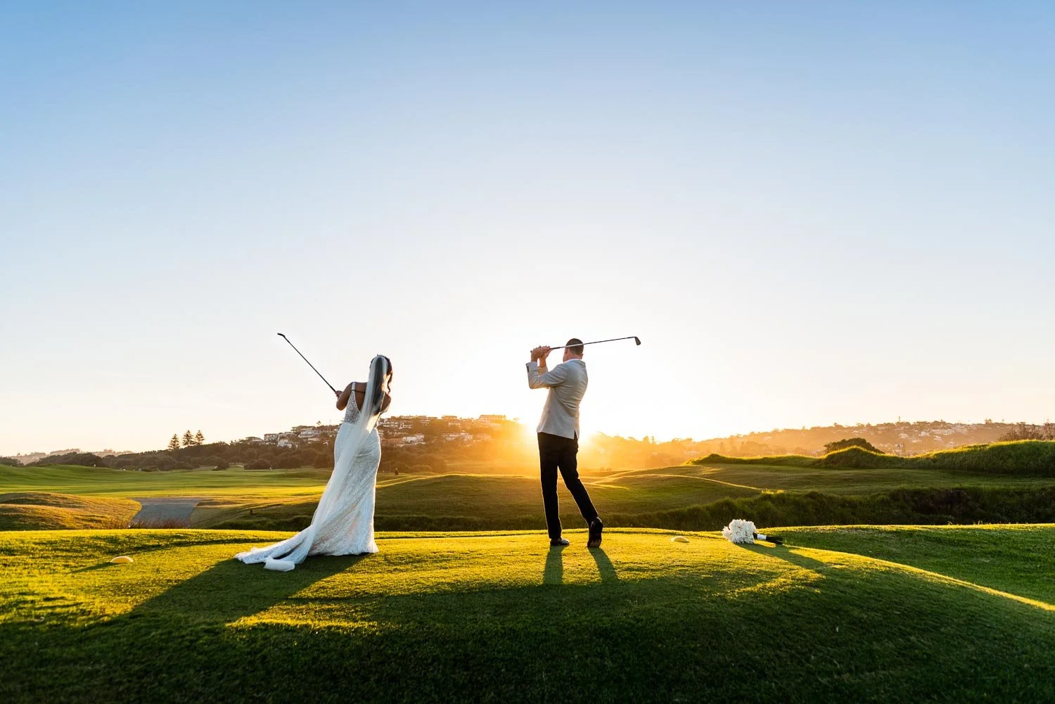Long Reef golf course wedding photo –  bride and groom playing golf, sunset