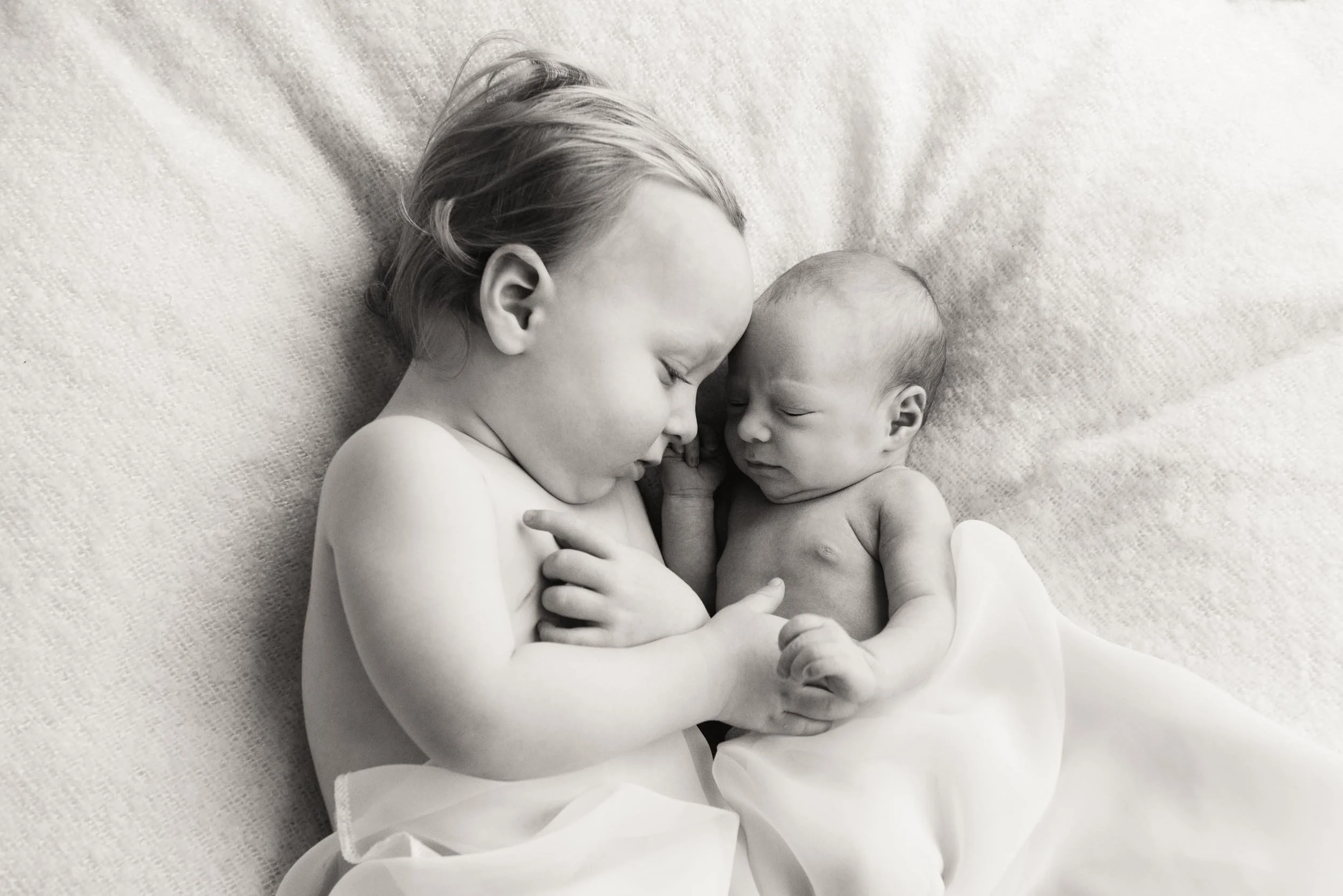 baby with big brother lying on bed for a newborn photography session in sydney