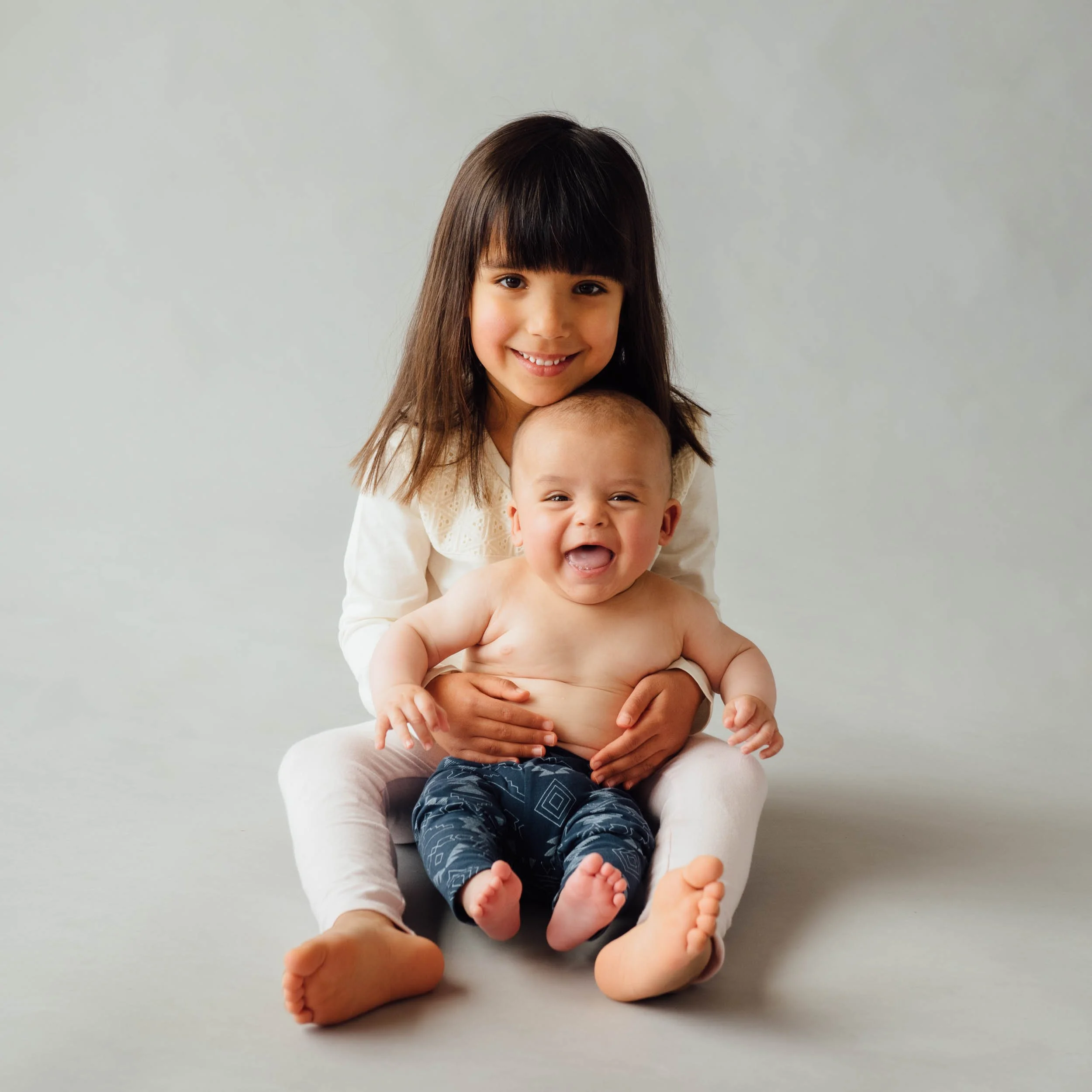 family baby photography of girl holding her laughing baby brother