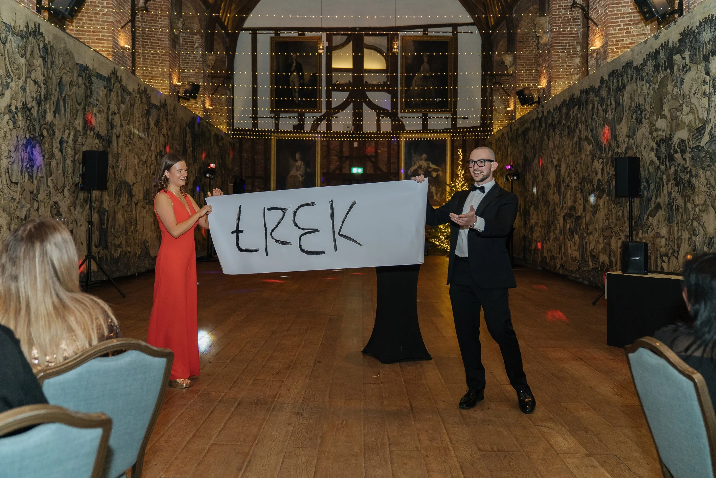 Magician and guest collaborating on a magic trick during the company gathering, entertaining the audience.