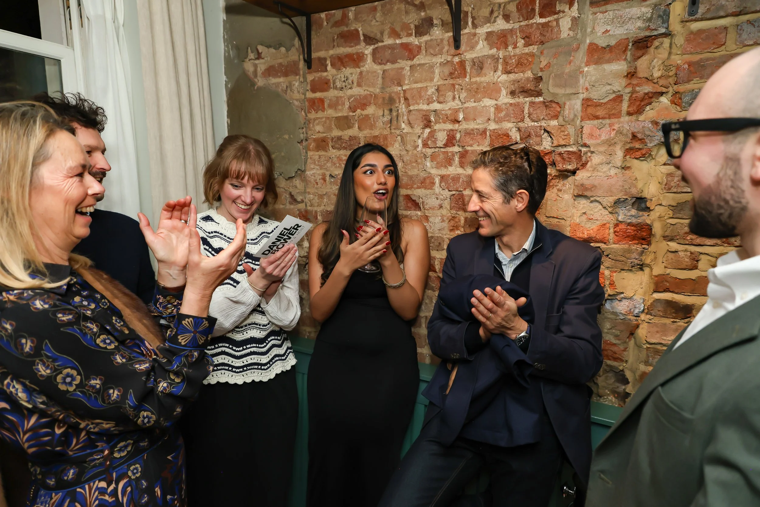 Guests applauding a close-up magic performance during a corporate reception.