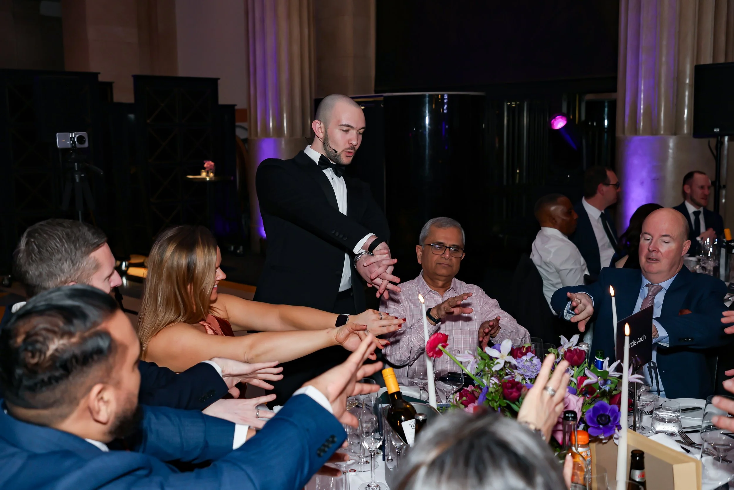 Corporate dinner guests taking part in an interactive table-side magic trick.
