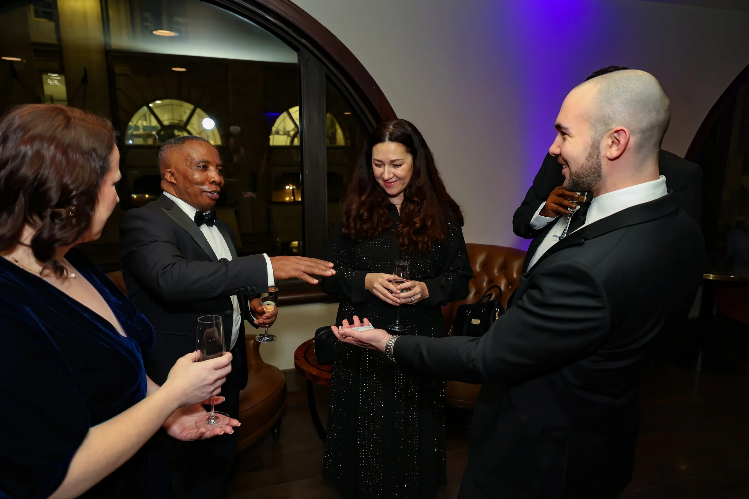Magician performing a close-up card trick to corporate associates at a business event.