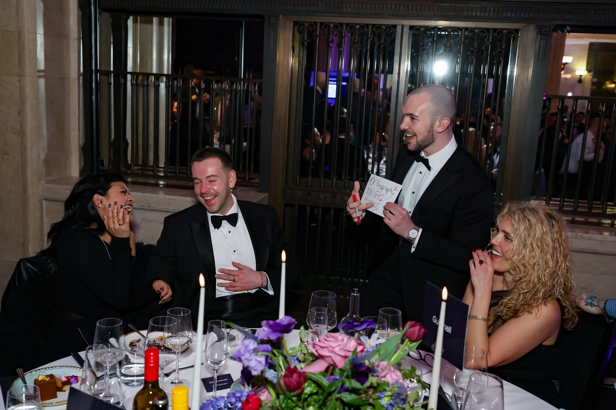 An engaging magician performing close-up magic for seated guests at a corporate dinner.