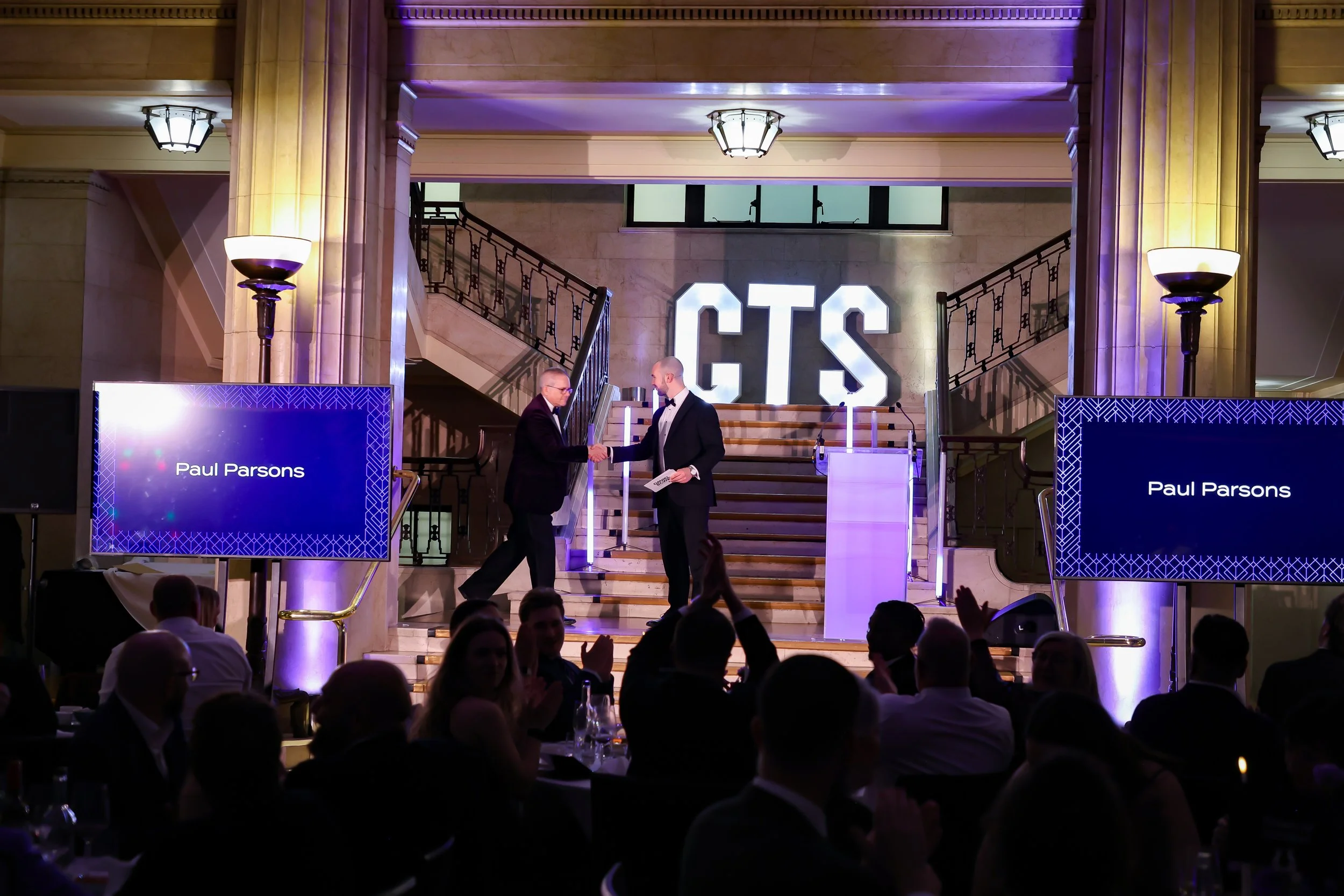 A professional magician involving a guest on stage as the crowd watches in anticipation.