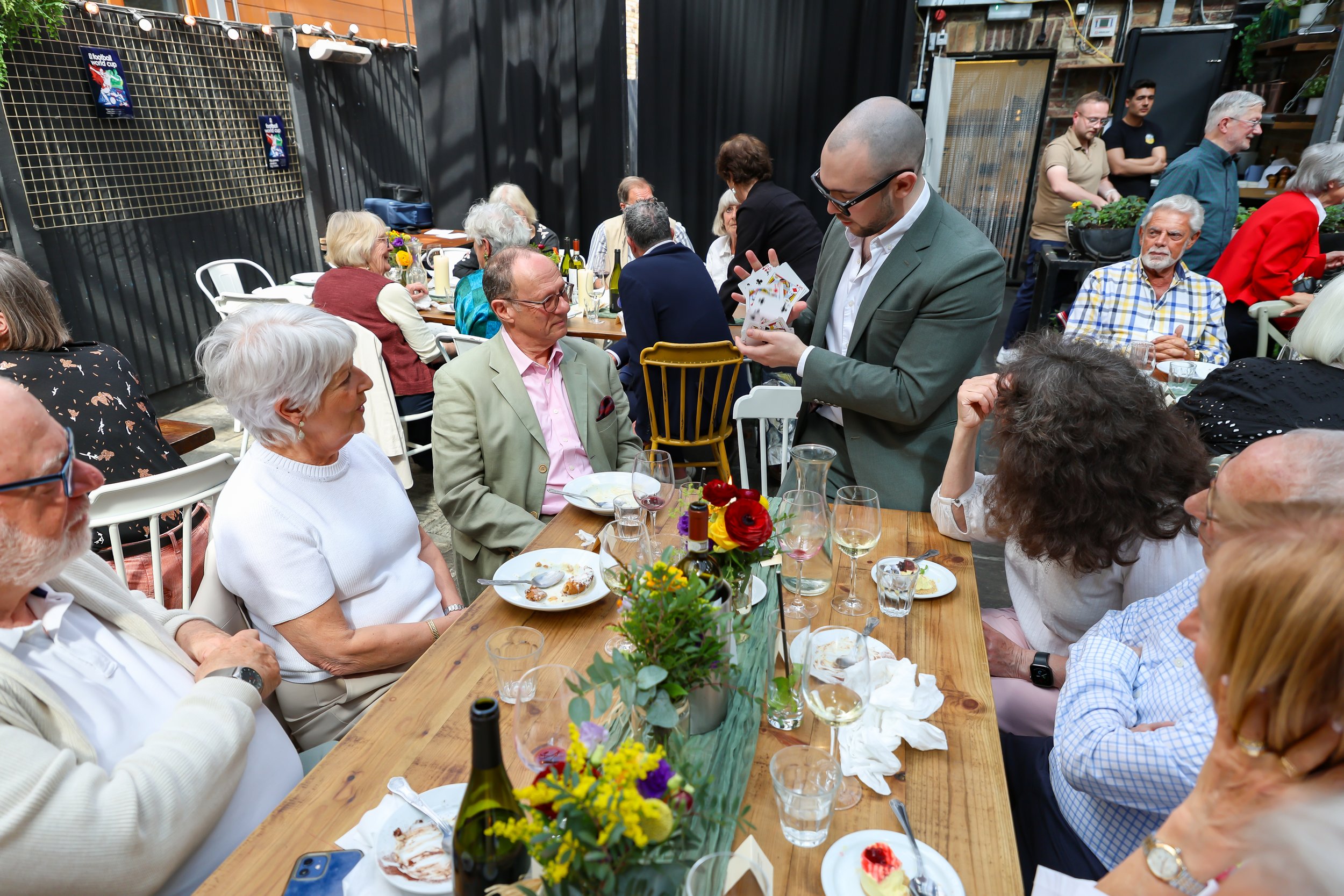 Guests attentively watch the Magician as he do his card tricks. 2026-May 3 Rhoda & Baruch Golden Anniversary. 
