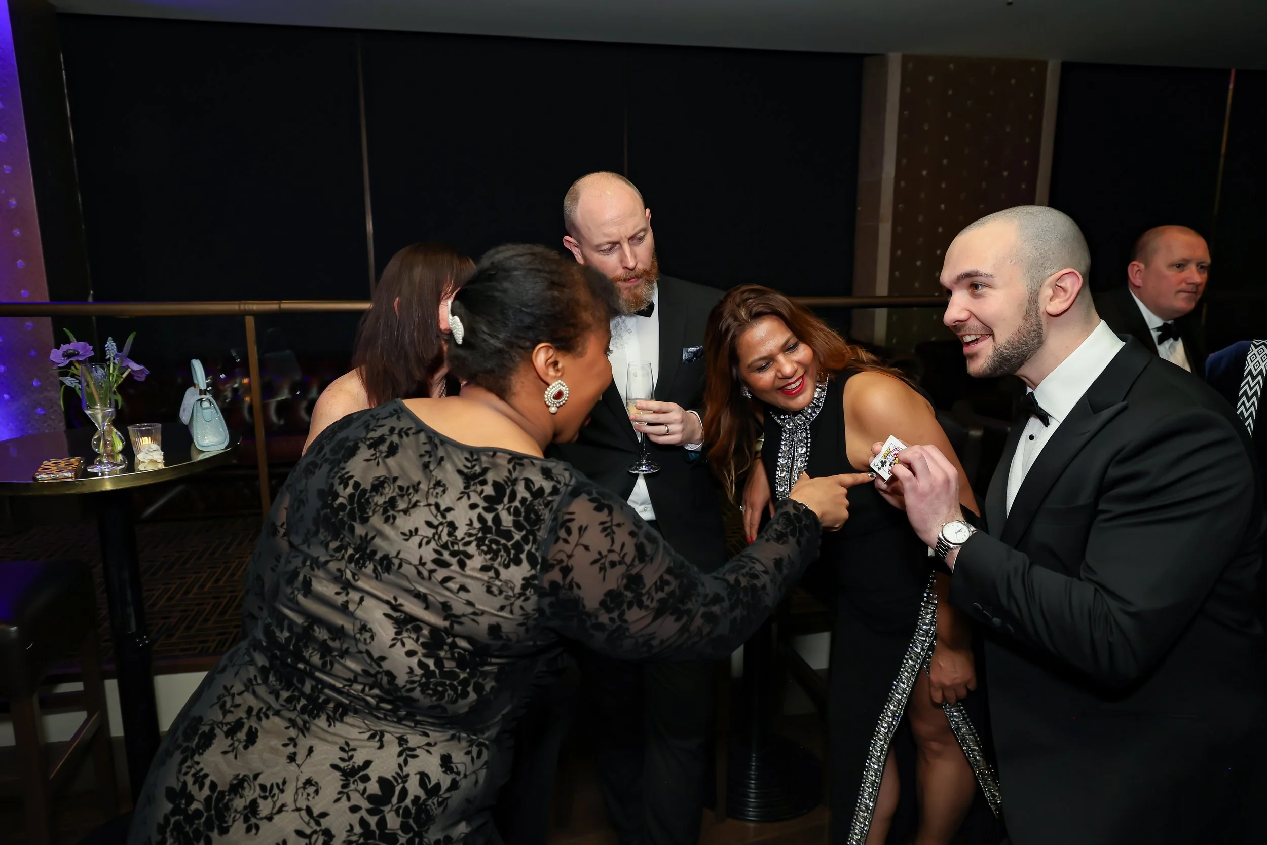 Corporate professionals enjoying with a live card performance by the magician during reception.