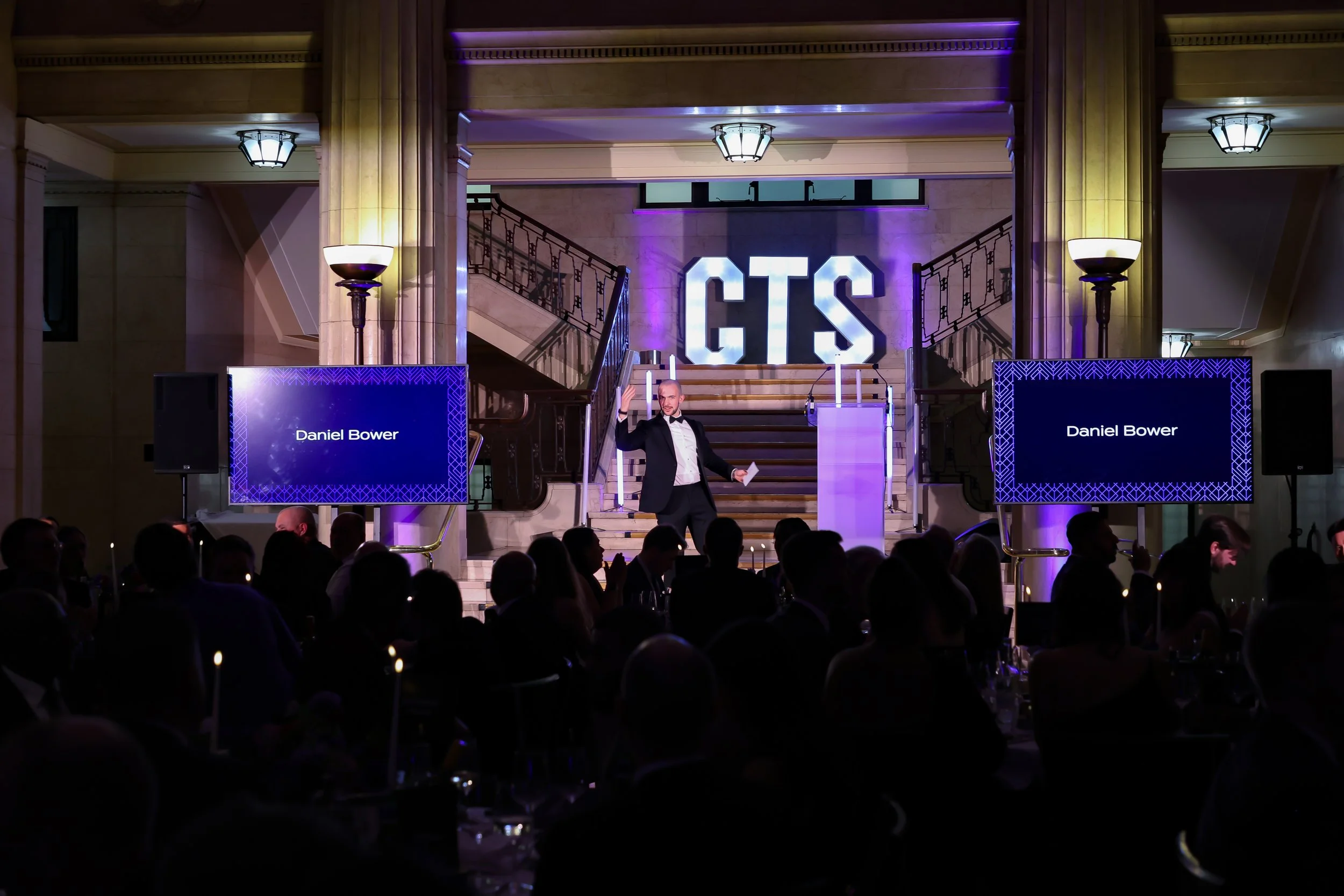 n engaging host directing an on-stage performance with a guest as the crowd responds.