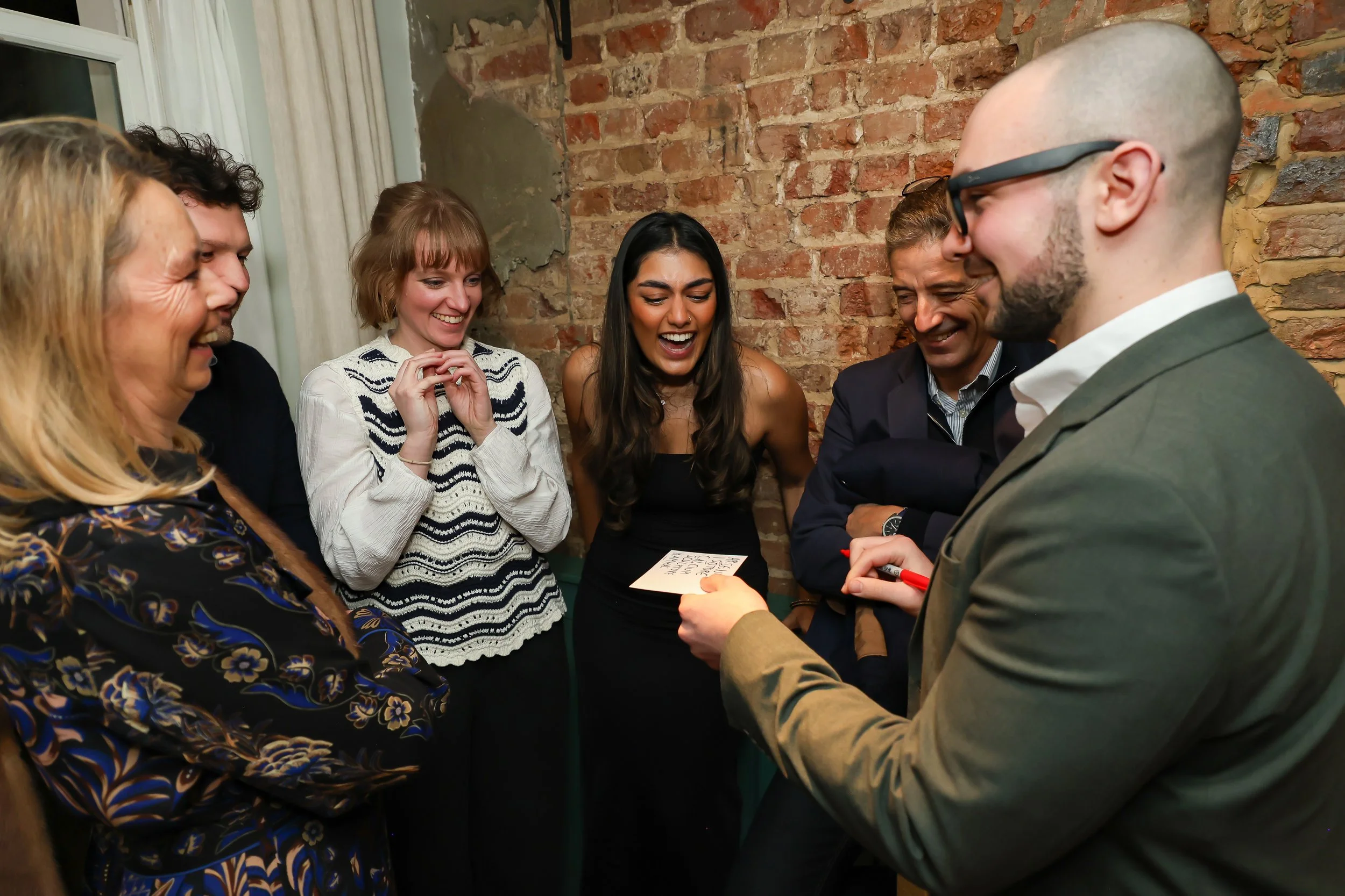 Guests applauding a close-up magic performance during a corporate reception.