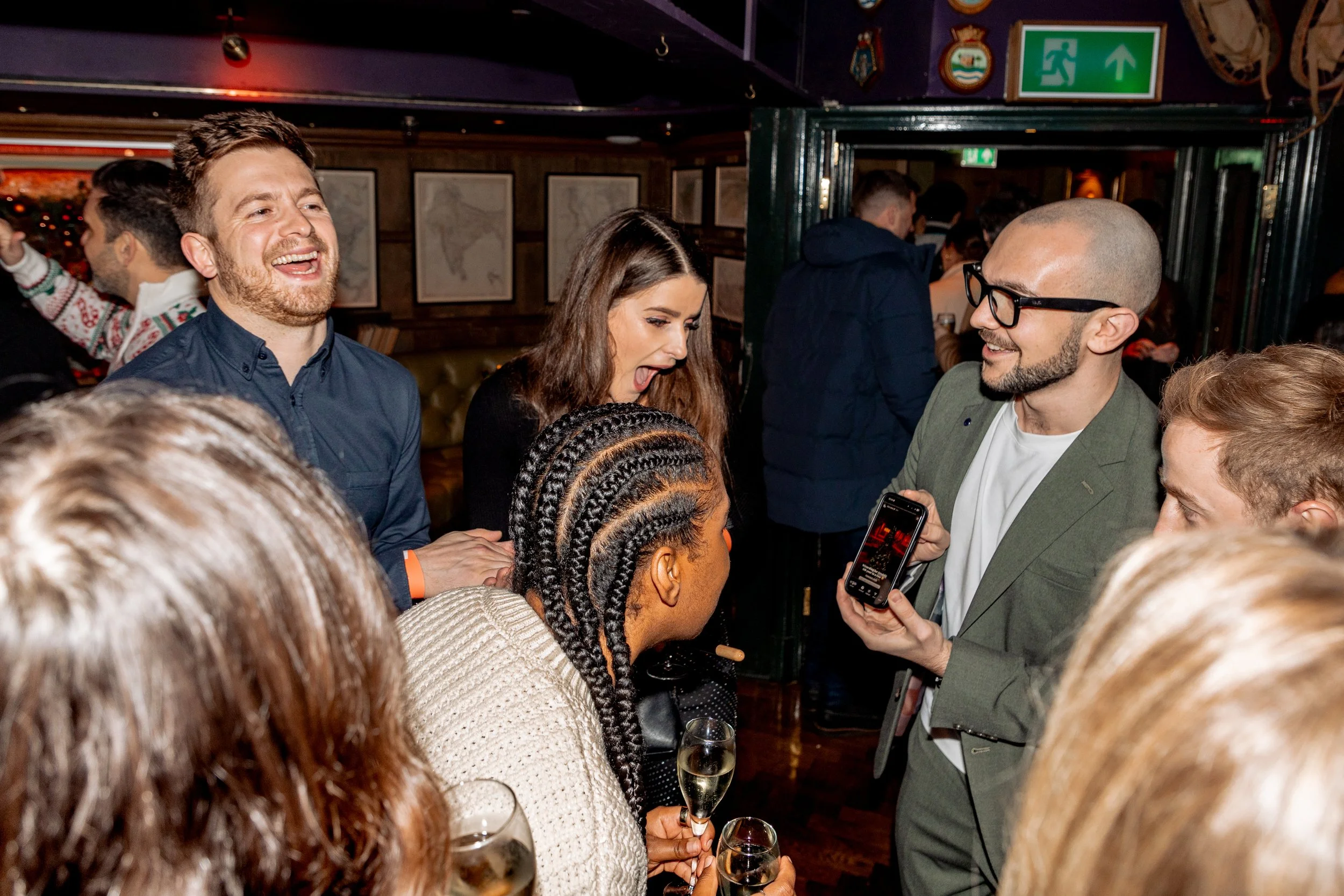 Employees amazed by magician performing walk-around tricks at company holiday event.