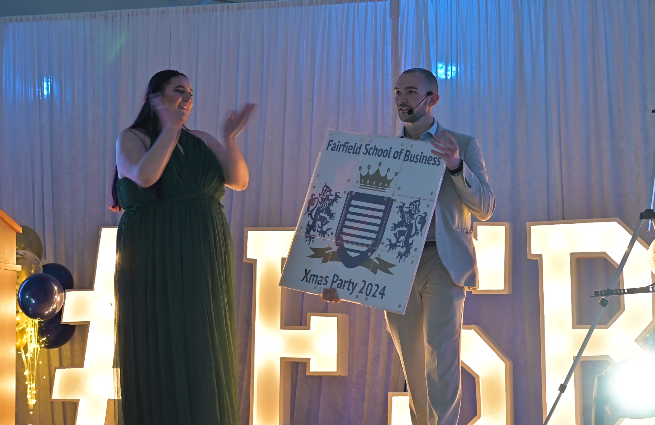 A magician on stage performing an interactive trick with a guest, captivating the audience.