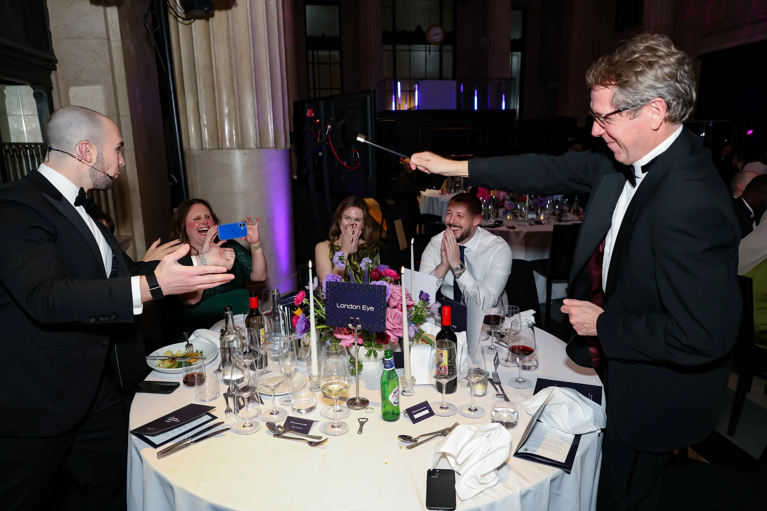 Close-up magic being performed for guests at their table, enhancing the dinner experience.