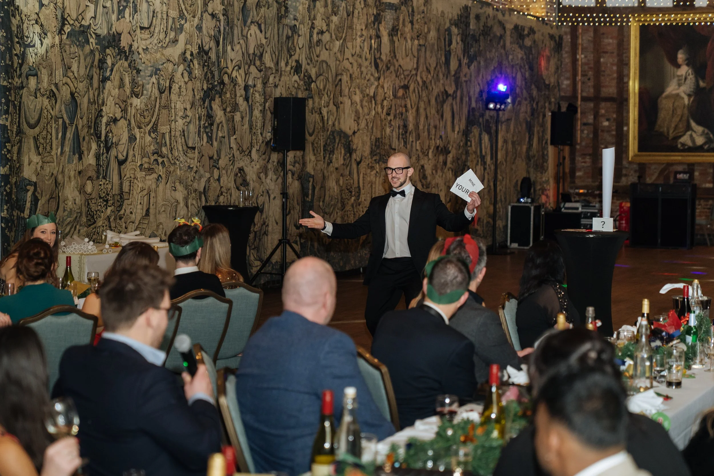 Magician performing card tricks in front of employees during christmas dinner.