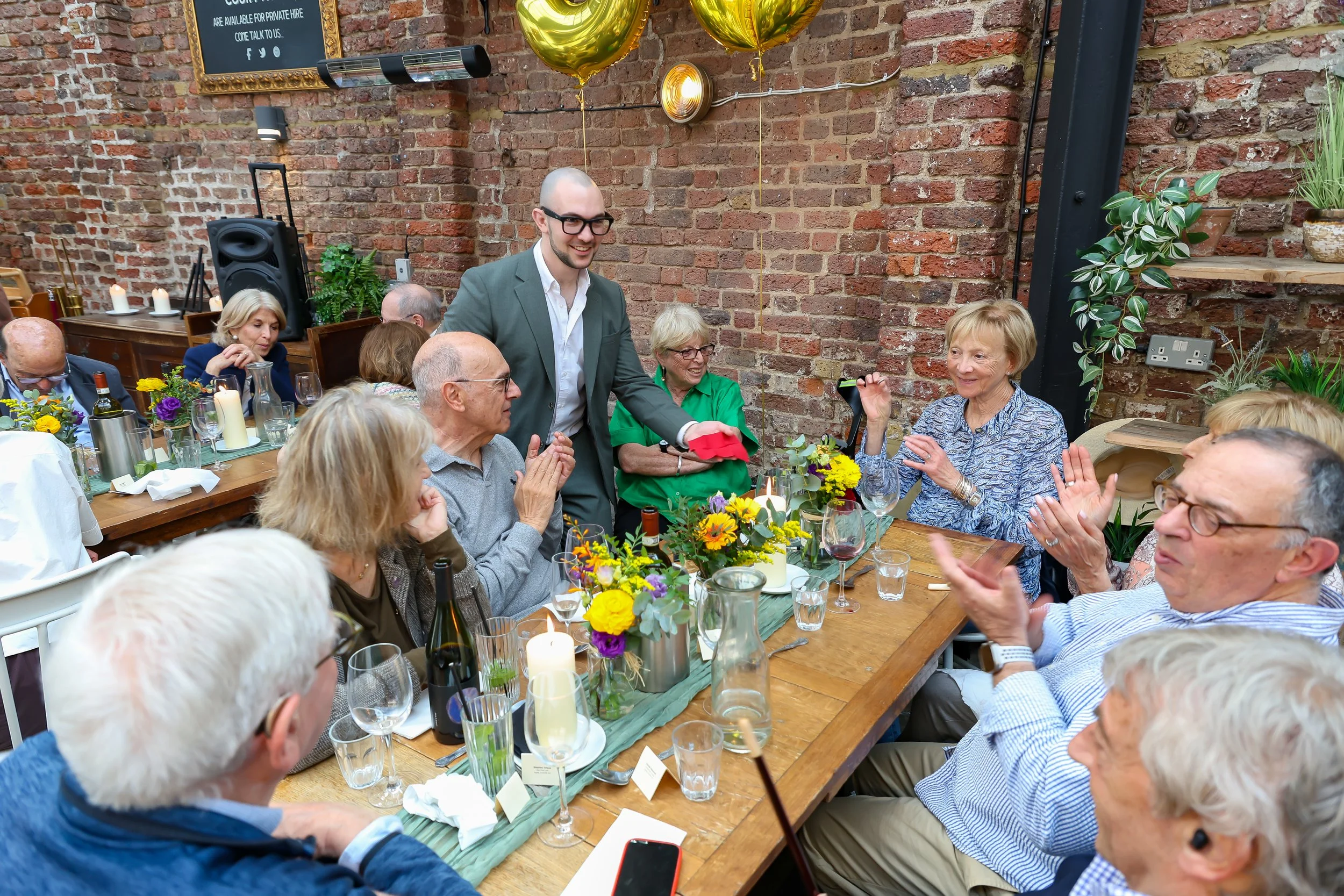 Guests enjoying on Magician mingling tricks. 2026-May 3 Rhoda & Baruch Golden Anniversary. 