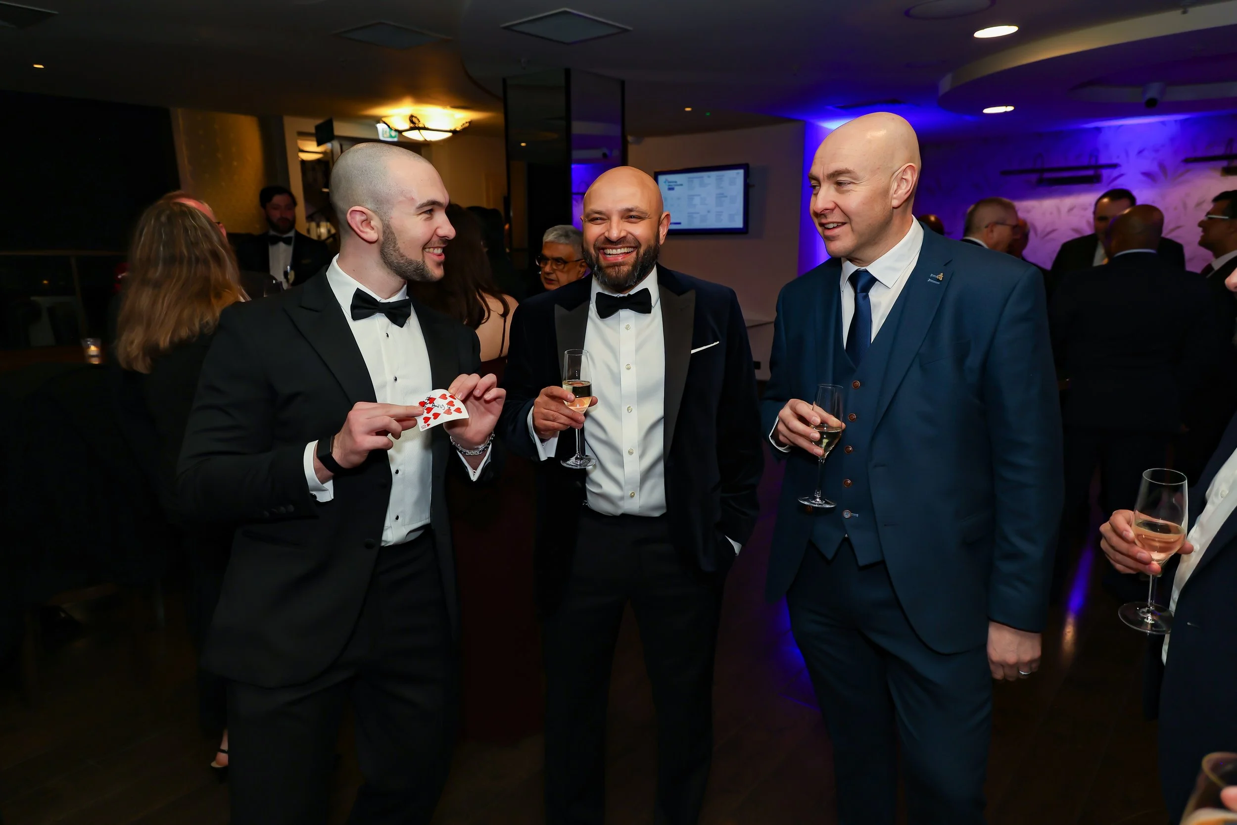 Close-up of a magician amazing corporate executives with sleight-of-hand card magic.