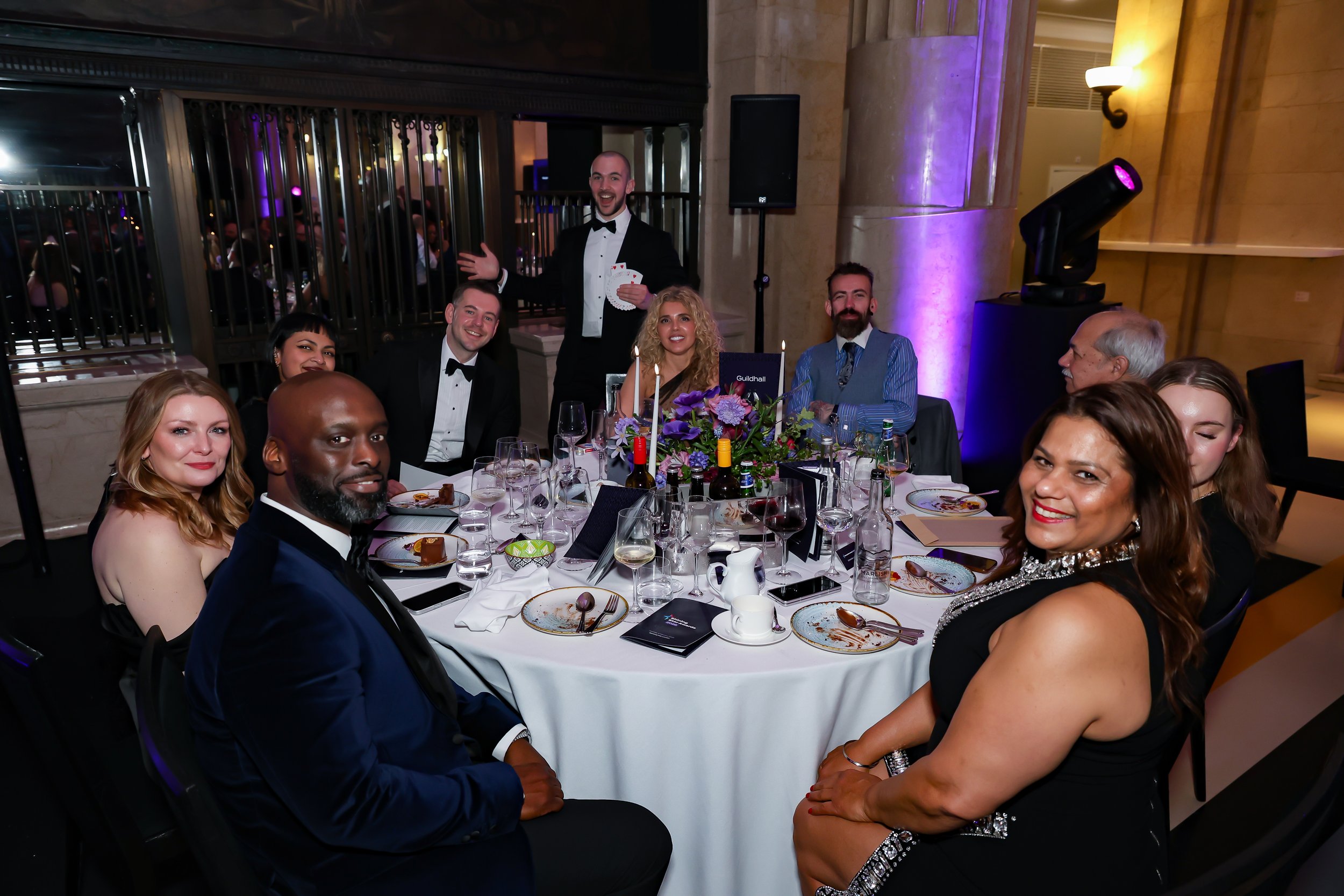 A professional magician delivering table magic during a formal corporate dinner.