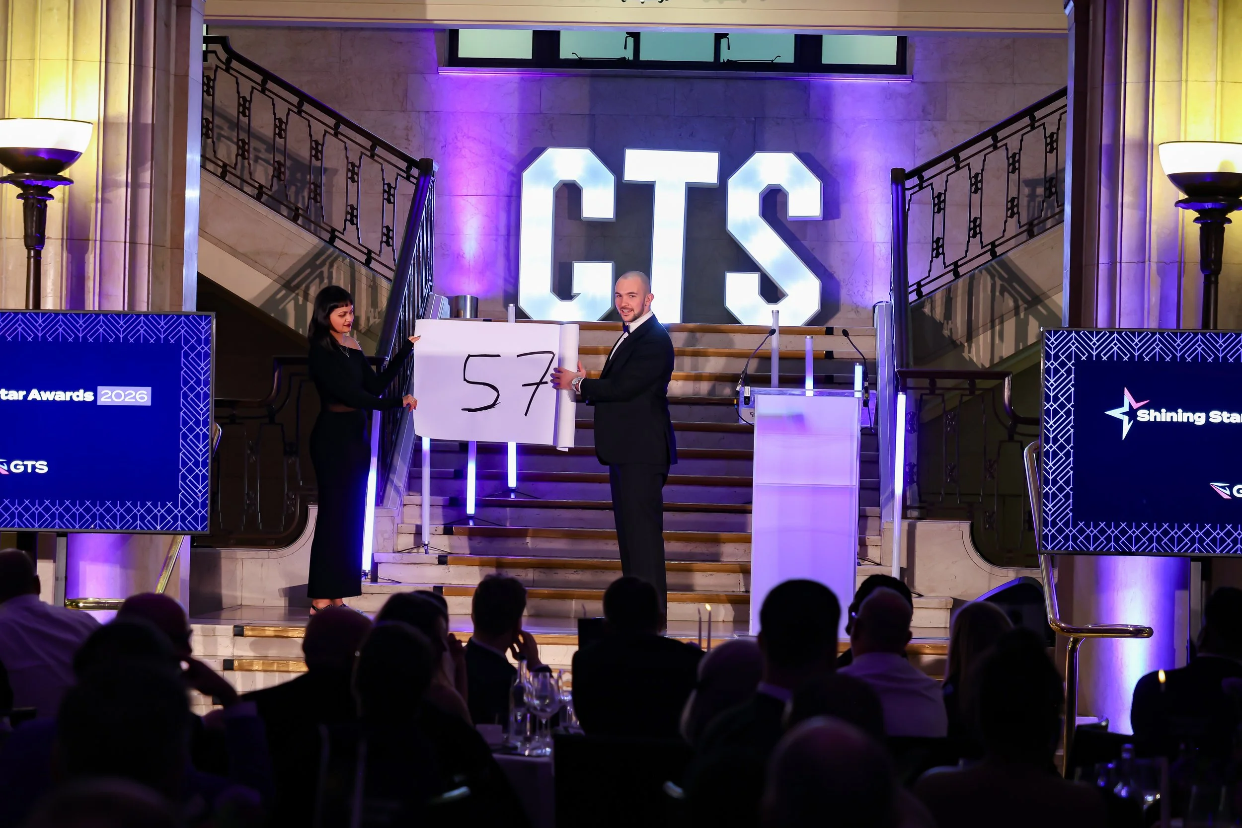 A professional magician involving a guest on stage as the crowd watches in anticipation.