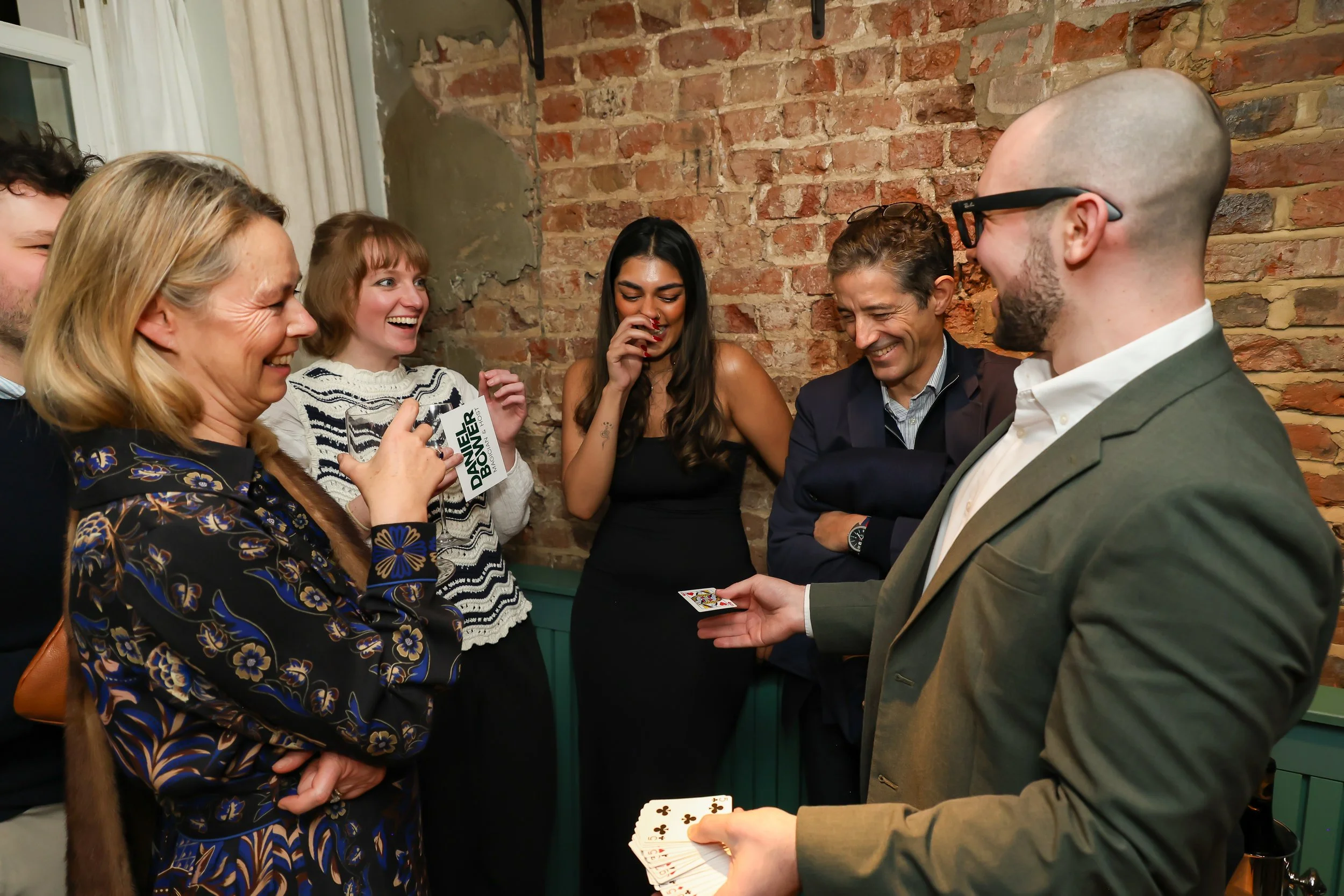 Playful close-up magic creating memorable reactions among guests at a corporate dinner.