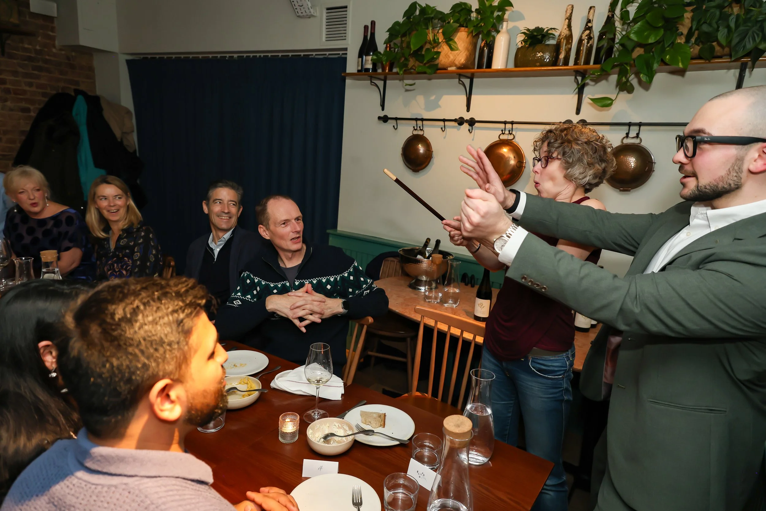 Magician performing close-up magic and involving guests during a corporate dinner.
