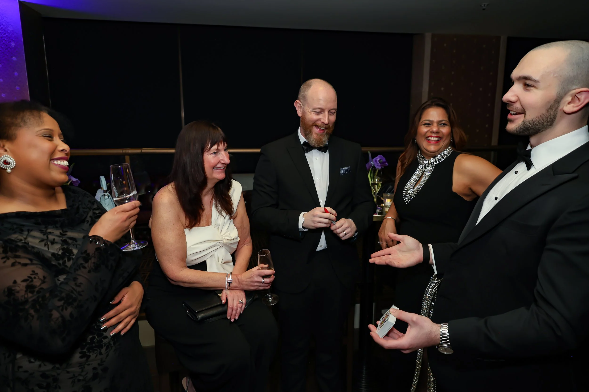 Corporate professionals enjoying with a live card performance by the magician during reception.