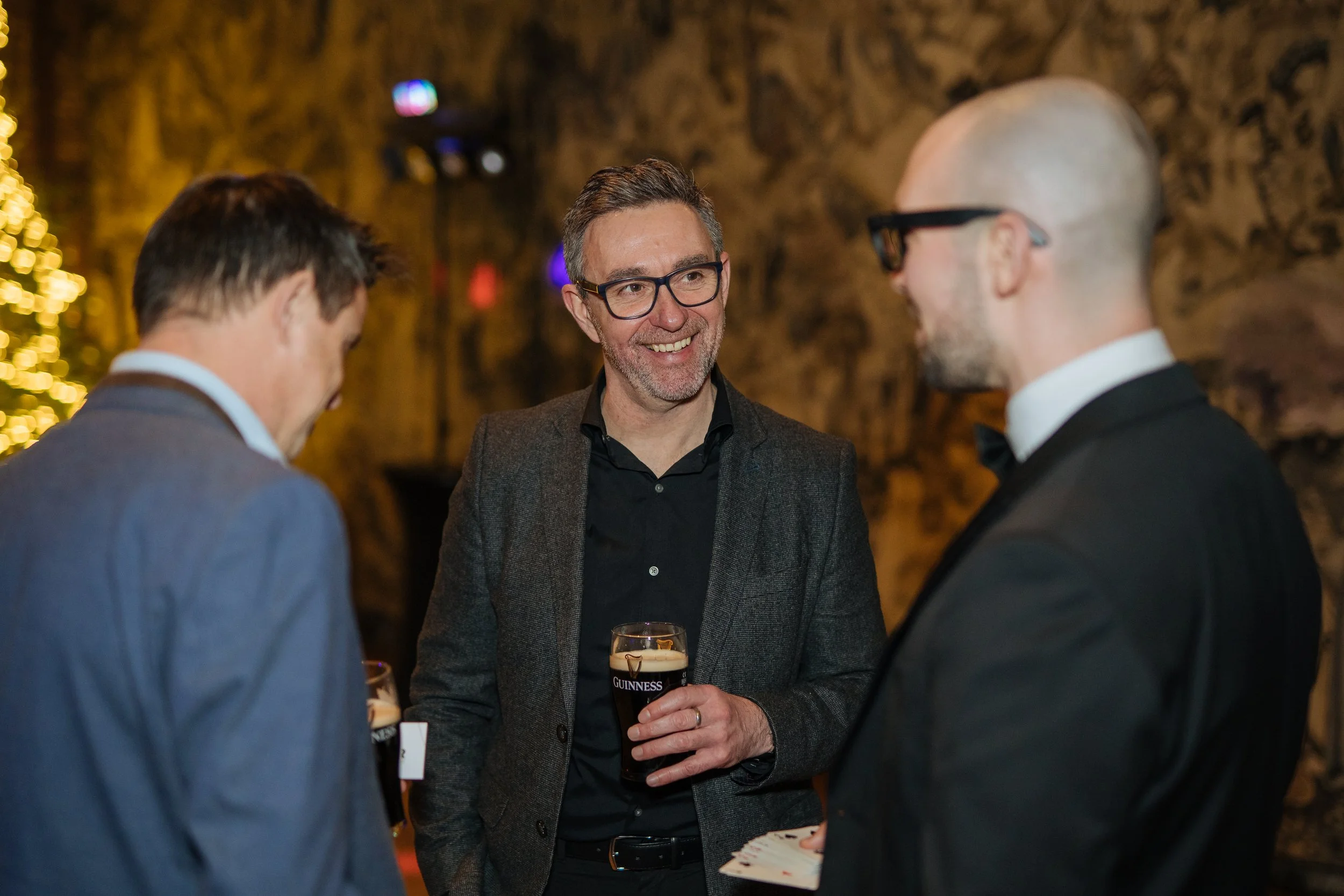Corporate magician performing close-up magic for corporate executives at event reception.