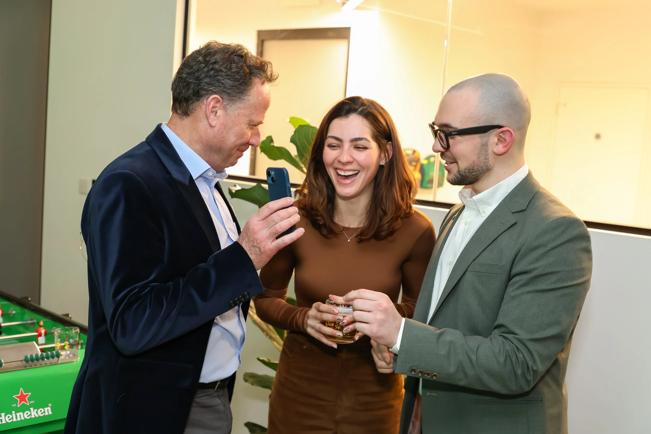 Guests burst into laughter as the magician performs close-up cellphone trick.