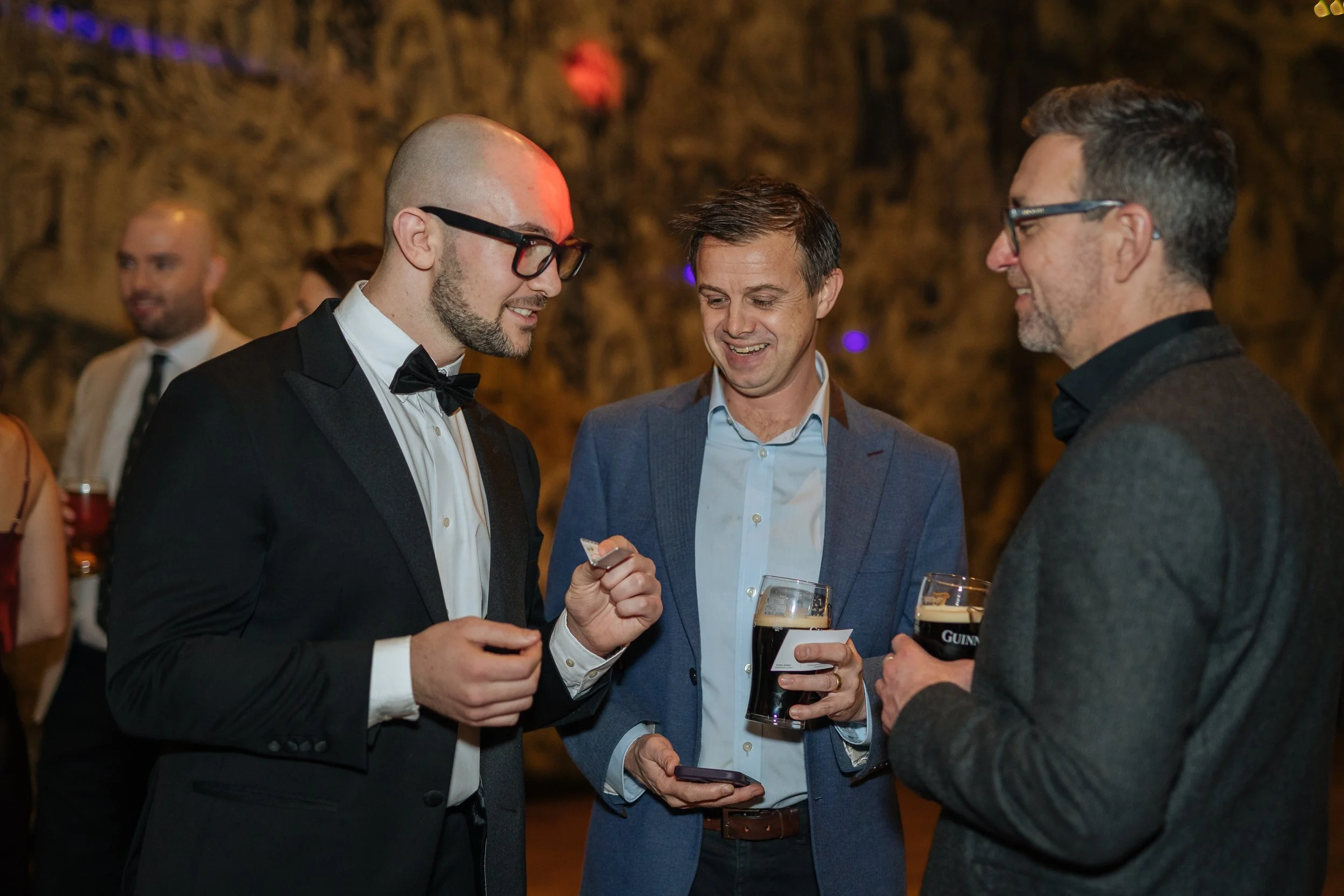 Corporate magician performing close-up magic for corporate executives at event reception.