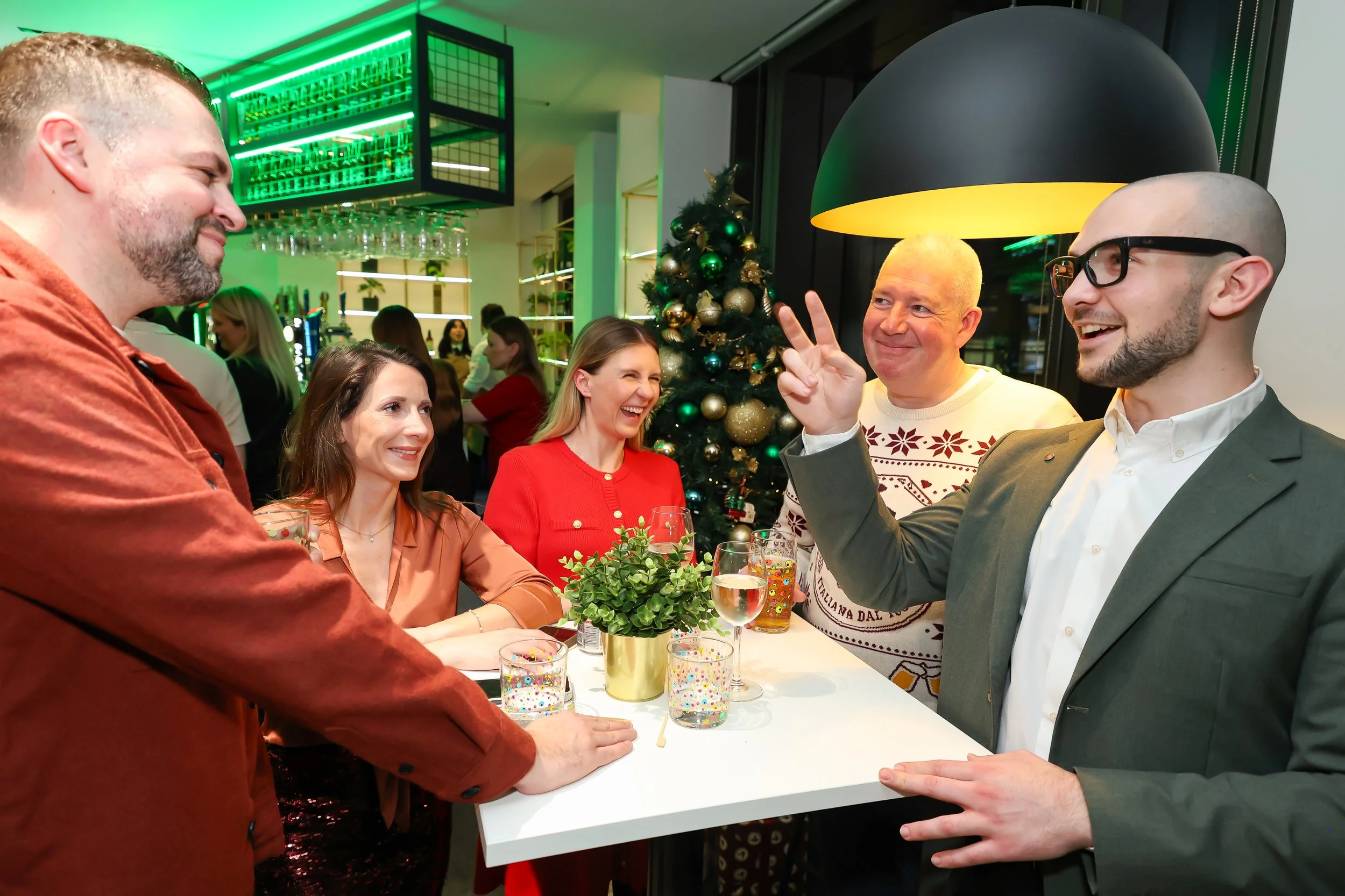 Corporate guests share laughter and astonishment during a playful magic trick at reception party. 