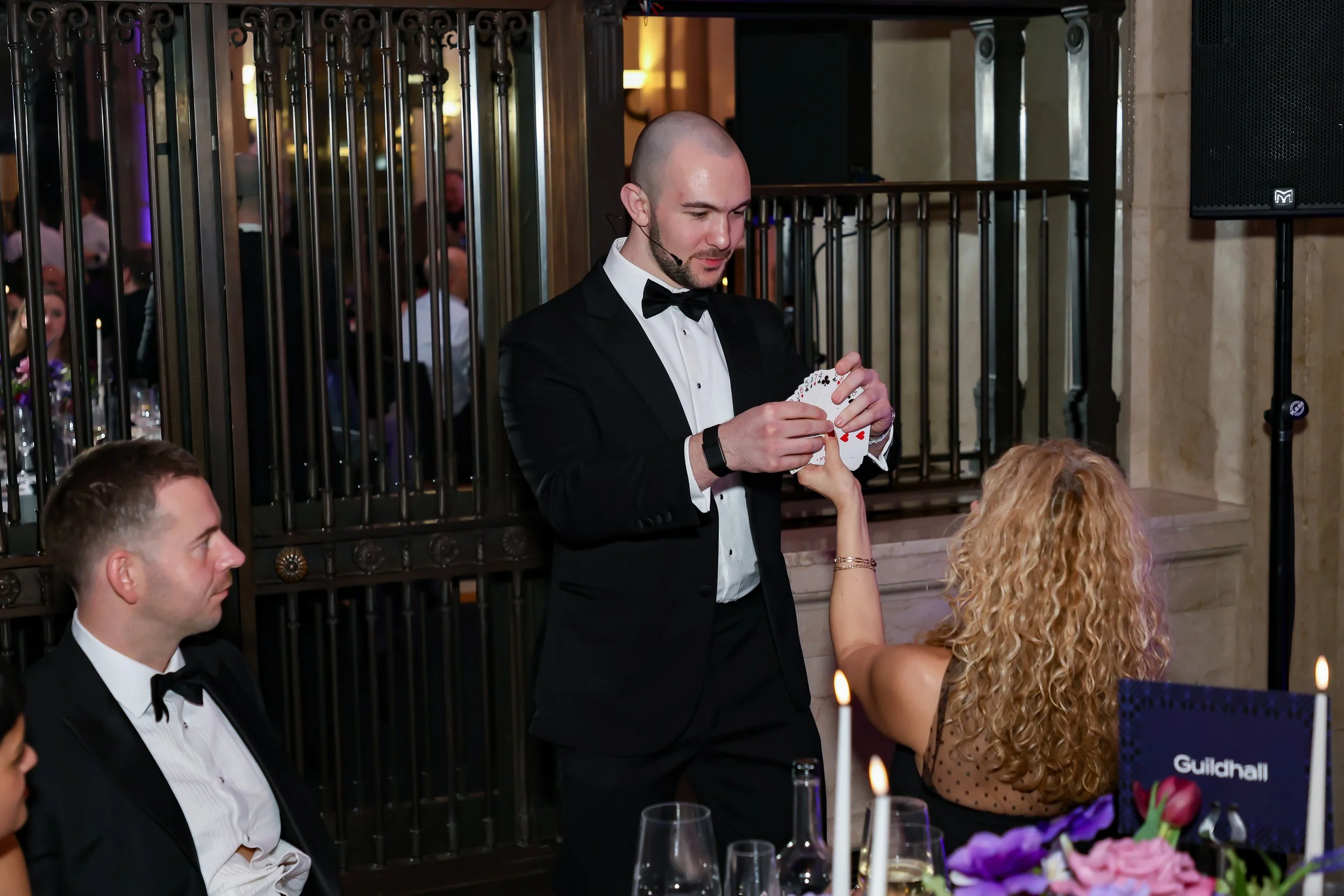 A magician performing intimate close-up tricks for guests at their table.