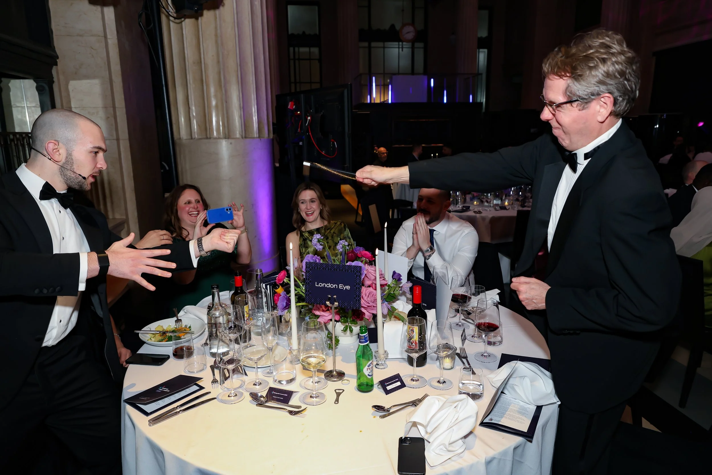 Close-up magic being performed for guests at their table, enhancing the dinner experience.